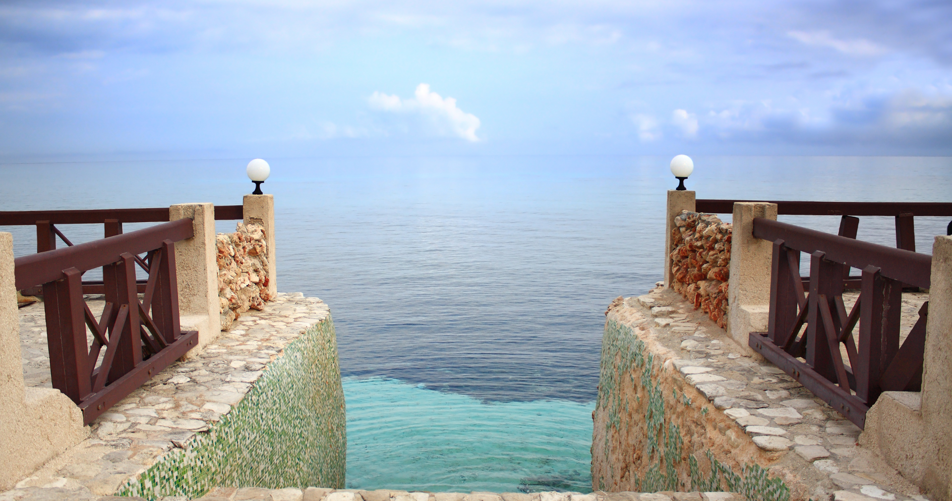 there is a bridge leading to the ocean with a view of the ocean .