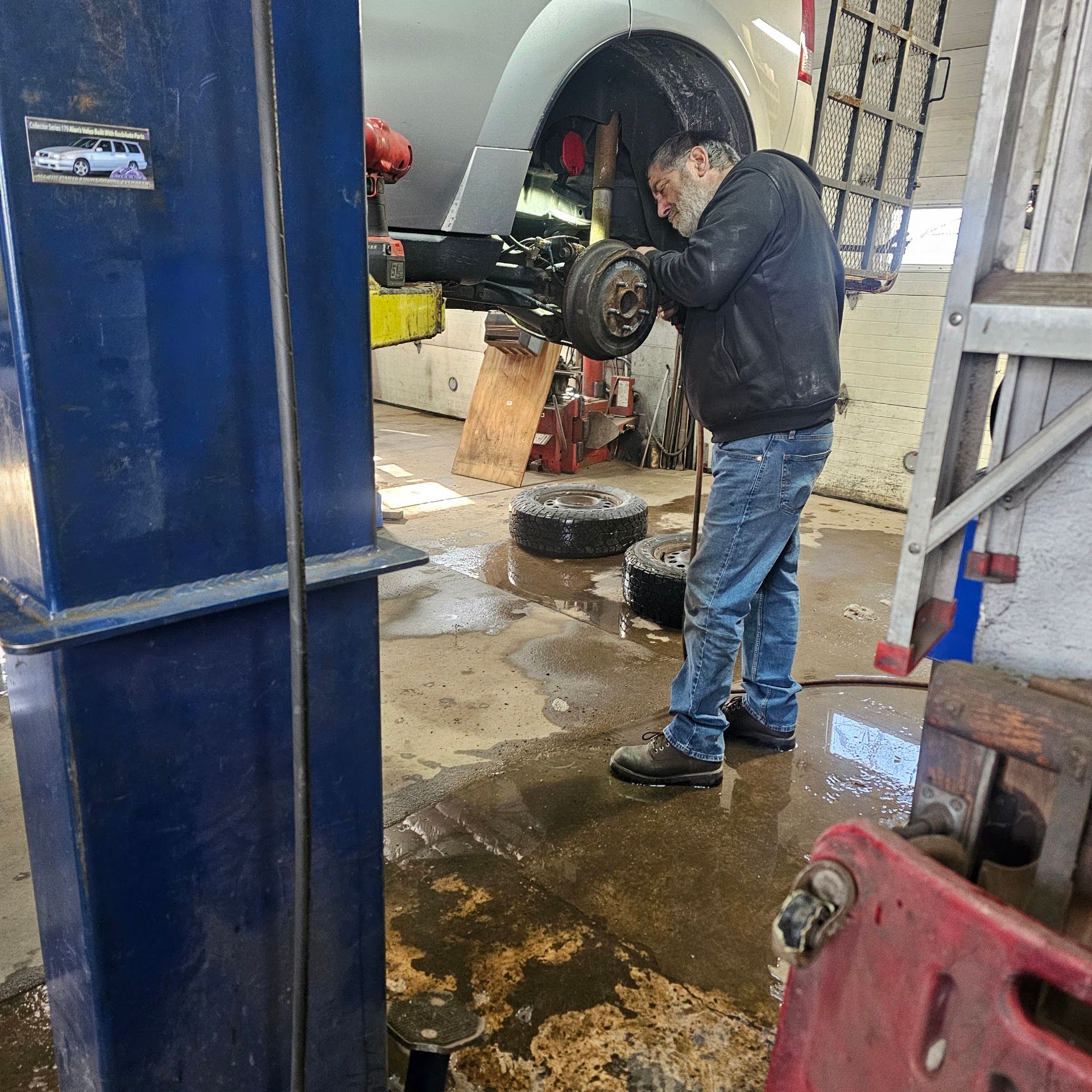 Mechanic working on a car wheel in a wet auto shop bay | Andre's Automotive Solutions LLC