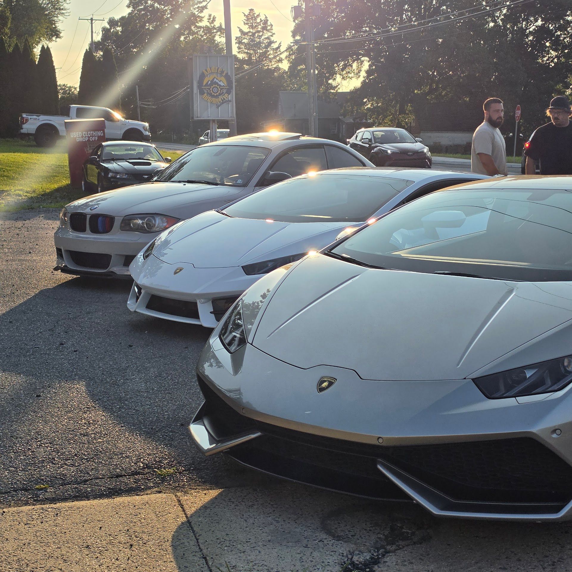 Three luxury sports cars parked at an outdoor car meet in evening sunlight Check Mark | Andre's Automotive Solutions LLC