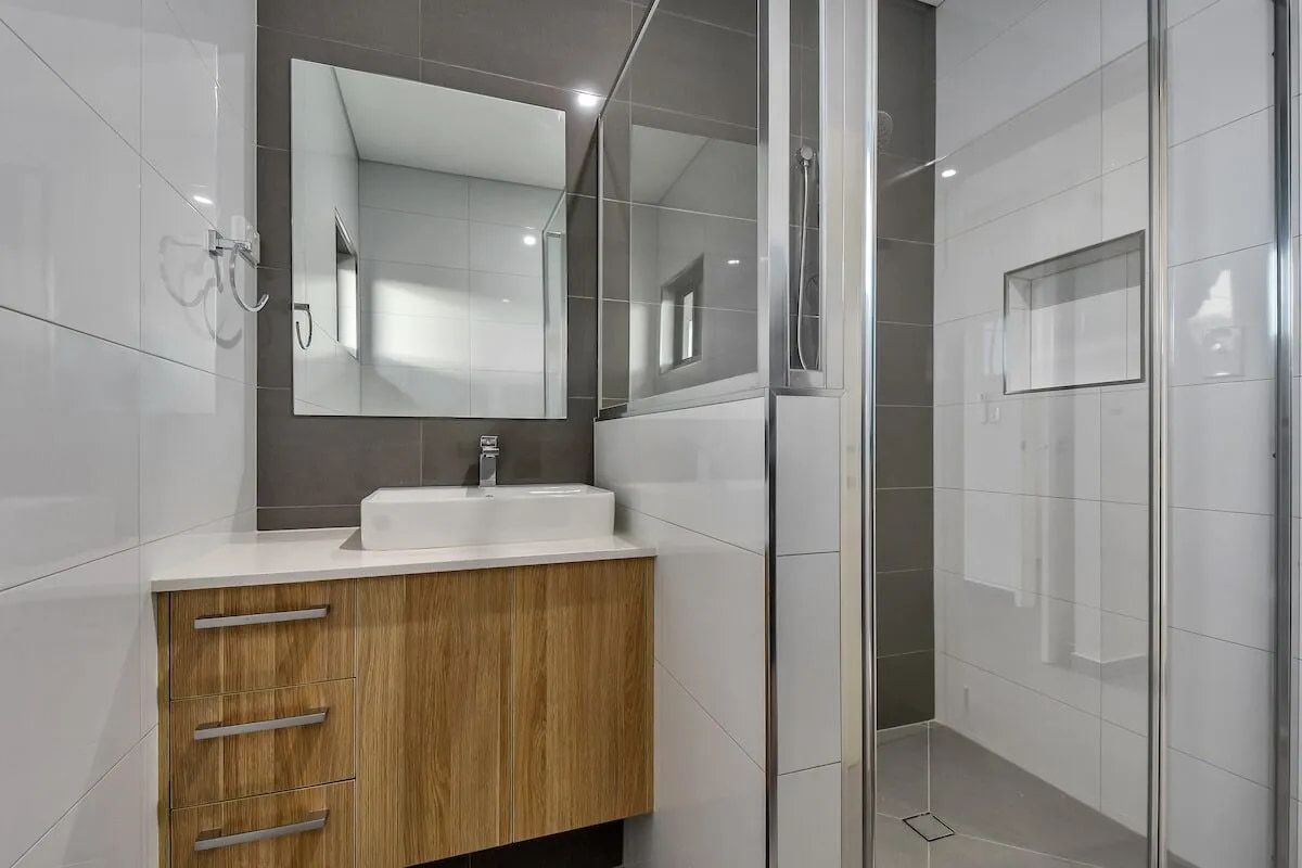 A Bathroom With a Sink, Mirror and Walk in Shower — Northern Tile Gallery in Winnellie, NT