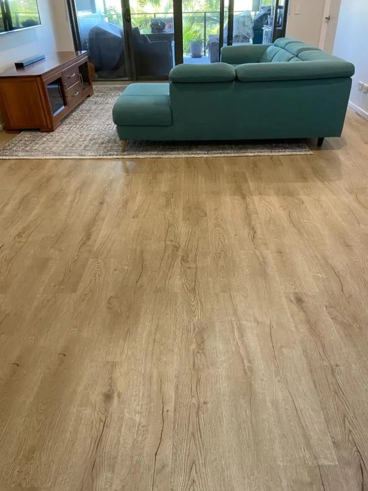 A Living Room With a Green Couch and a Wooden Floor — Northern Tile Gallery in Winnellie, NT