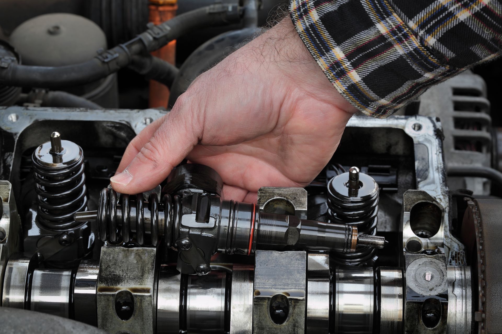 Hand inspecting a car engine’s camshaft and valve springs under the hood