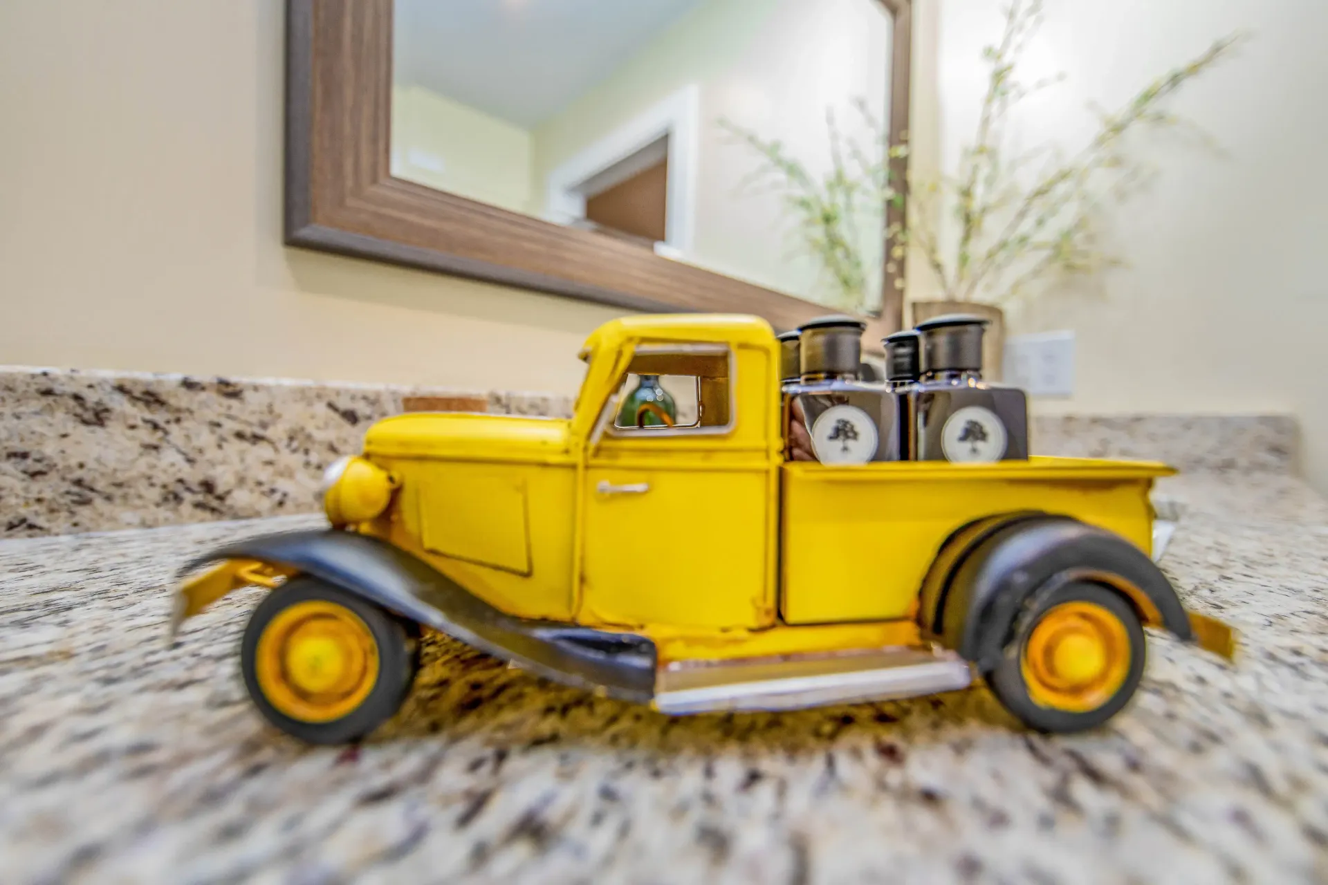 A yellow toy truck is sitting on a counter next to a mirror.