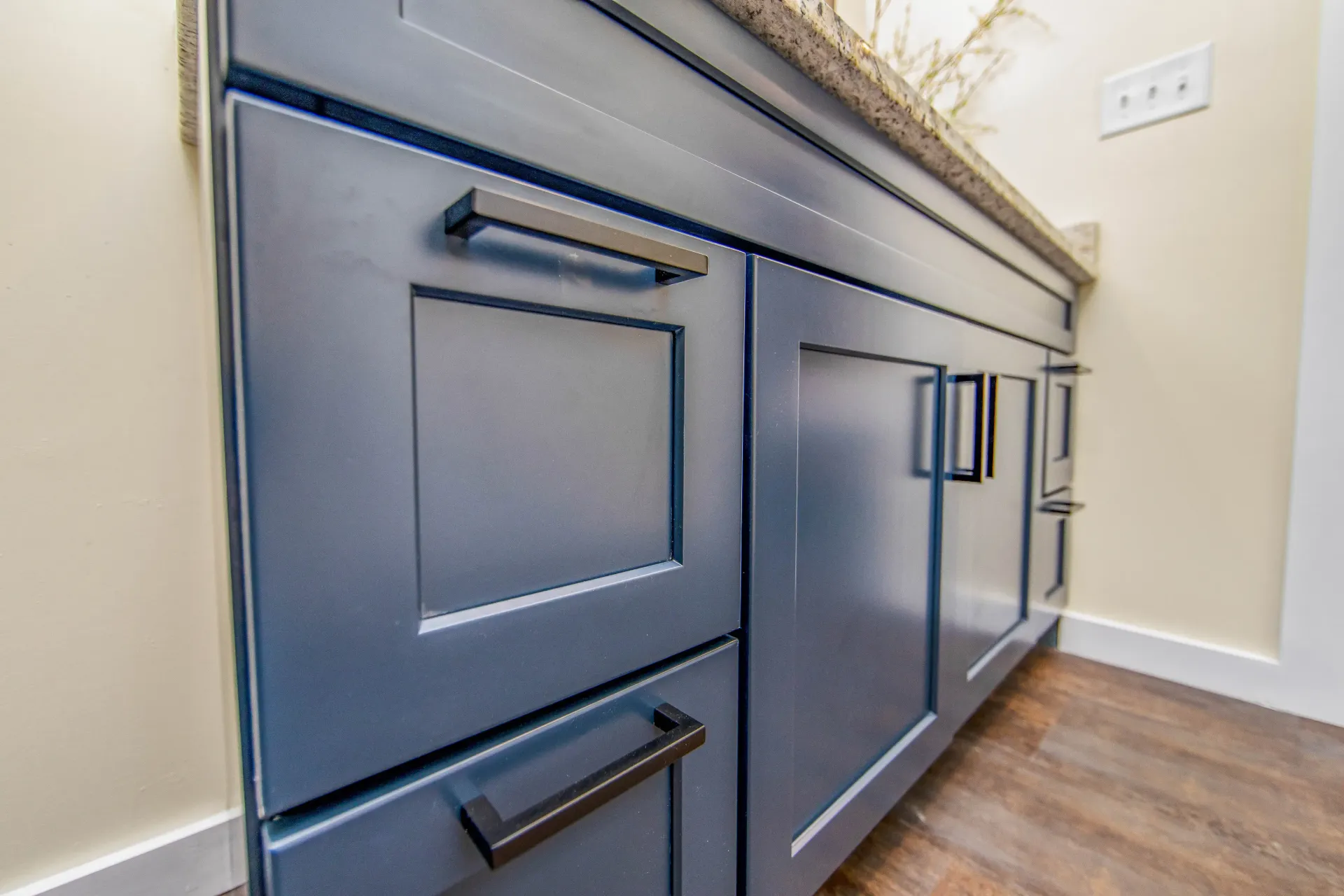 A bathroom vanity with blue cabinets and black handles.