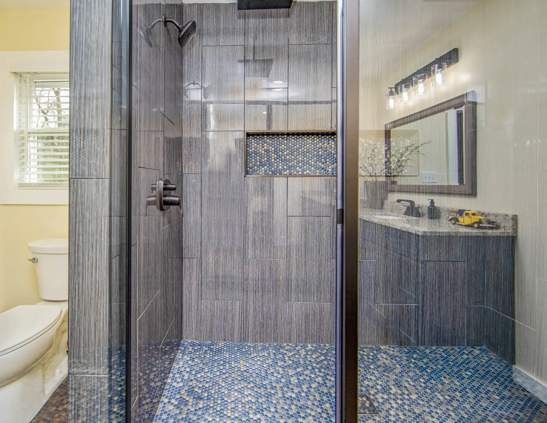 A bathroom with a walk in shower , toilet , sink and mirror.