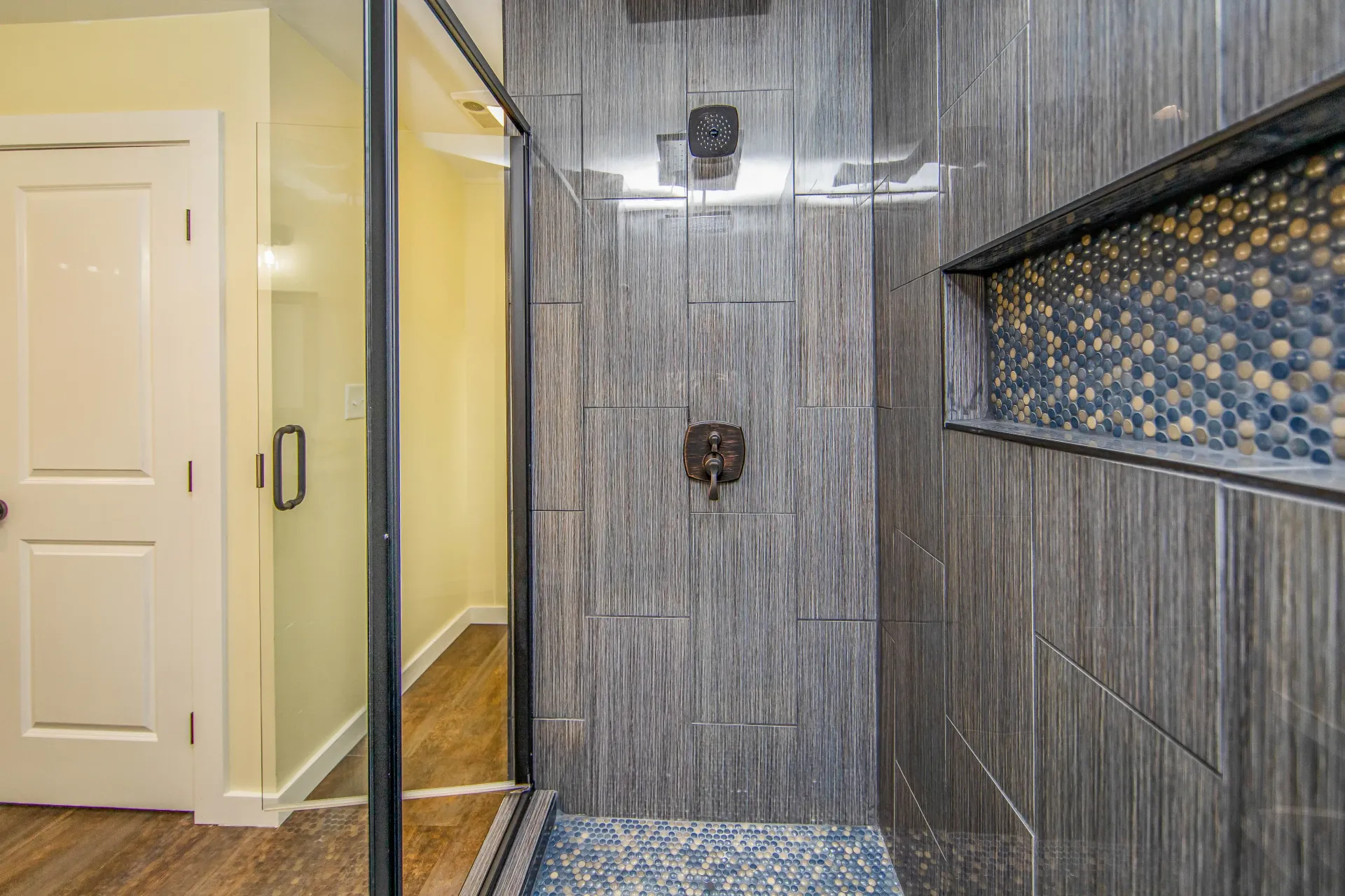 A bathroom with a walk in shower and a glass door.