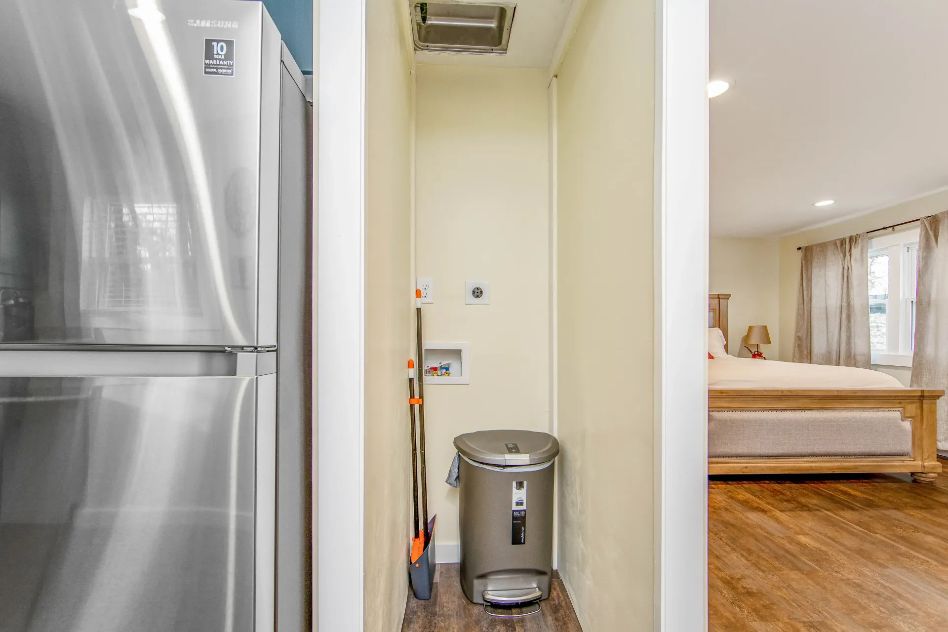 A stainless steel refrigerator is sitting next to a trash can in a room.