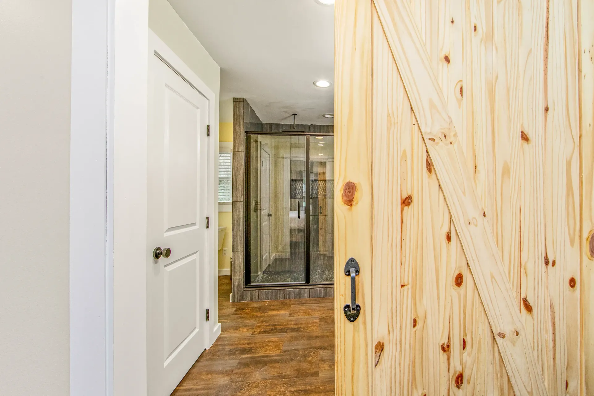 A bathroom with a sliding barn door and a walk in shower.