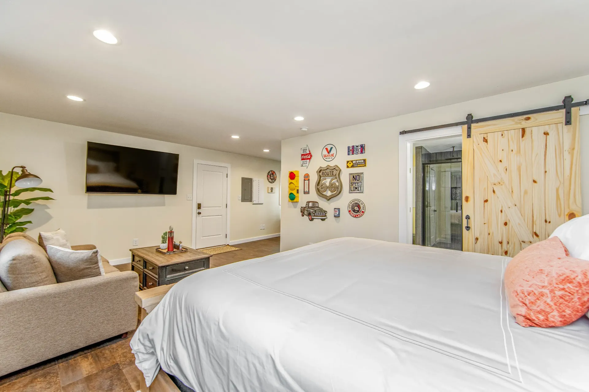 A bedroom with a large bed , couch , television and sliding barn doors.