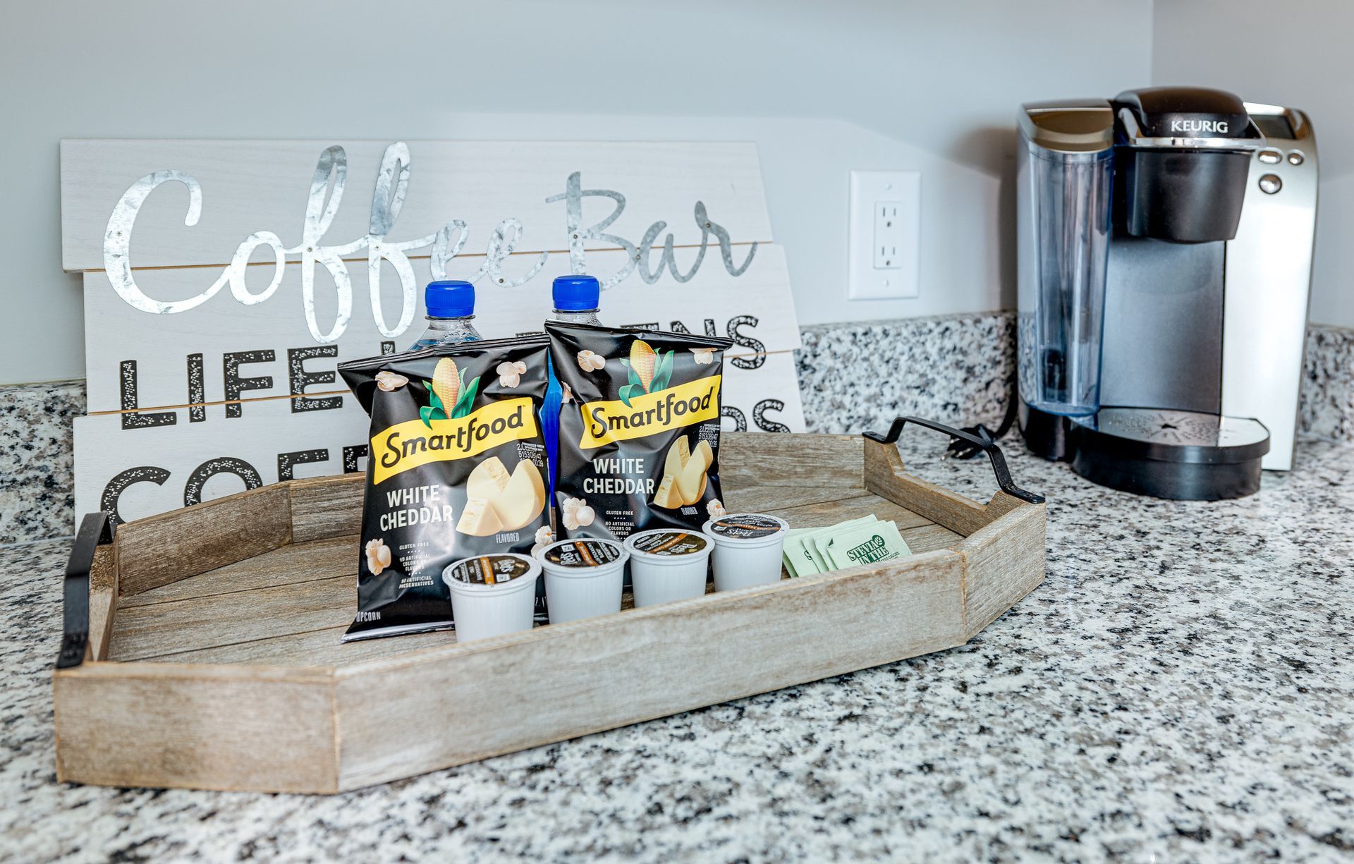 A tray of snacks and coffee cups on a counter next to a coffee maker.