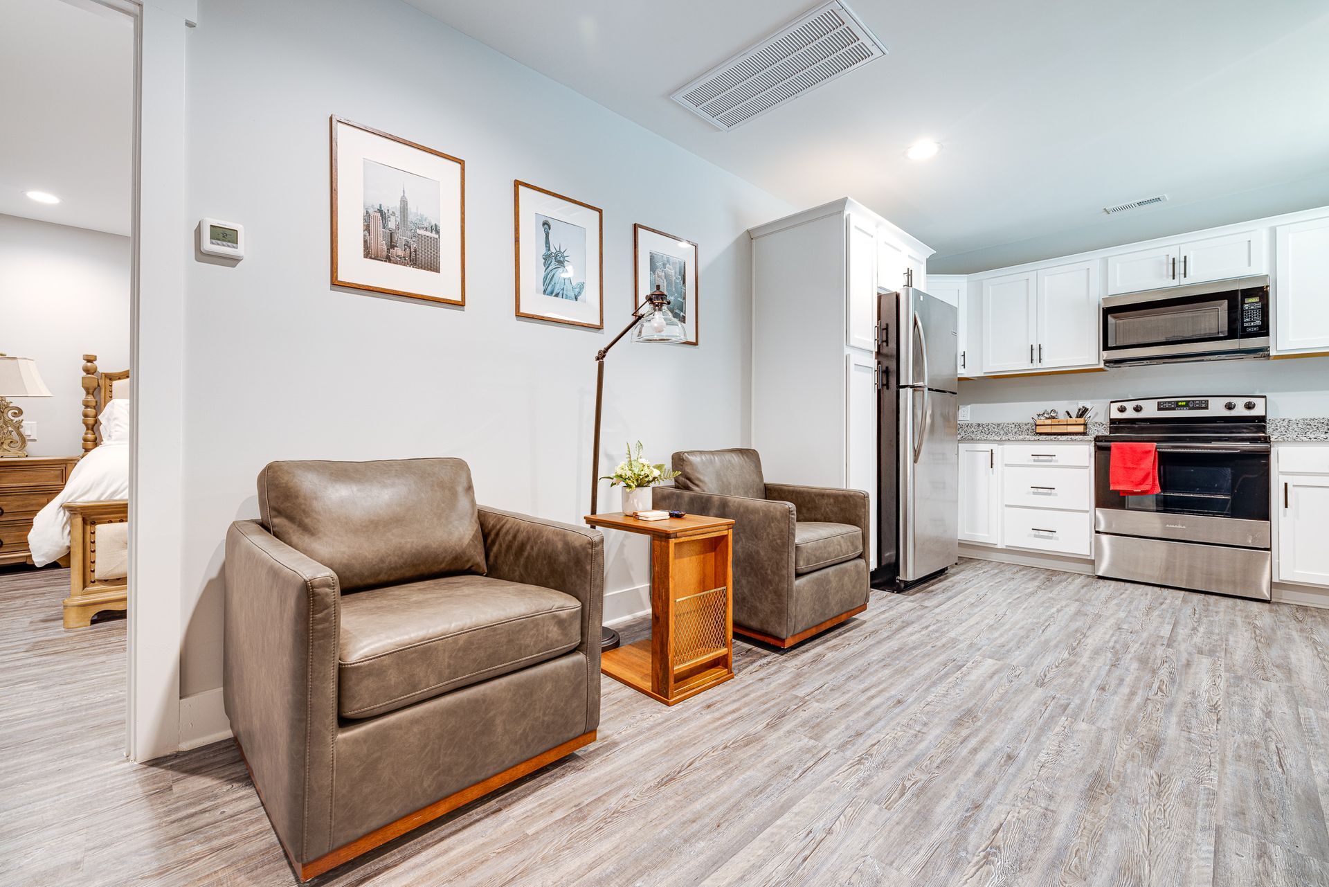 A living room with two chairs and a table in front of a kitchen.