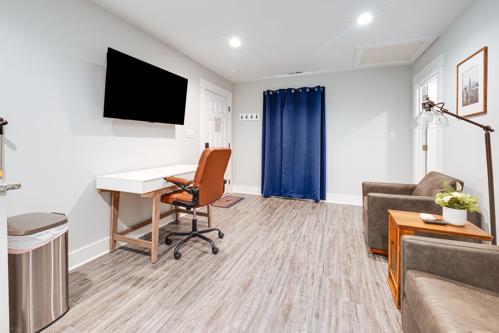 A living room with a desk , chair , television and couch.