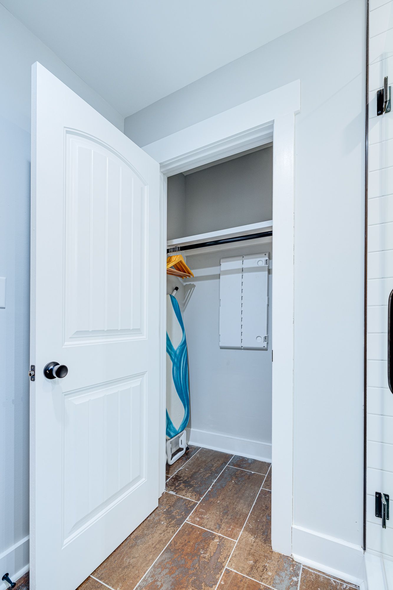 A laundry room with a white door and a tiled floor.