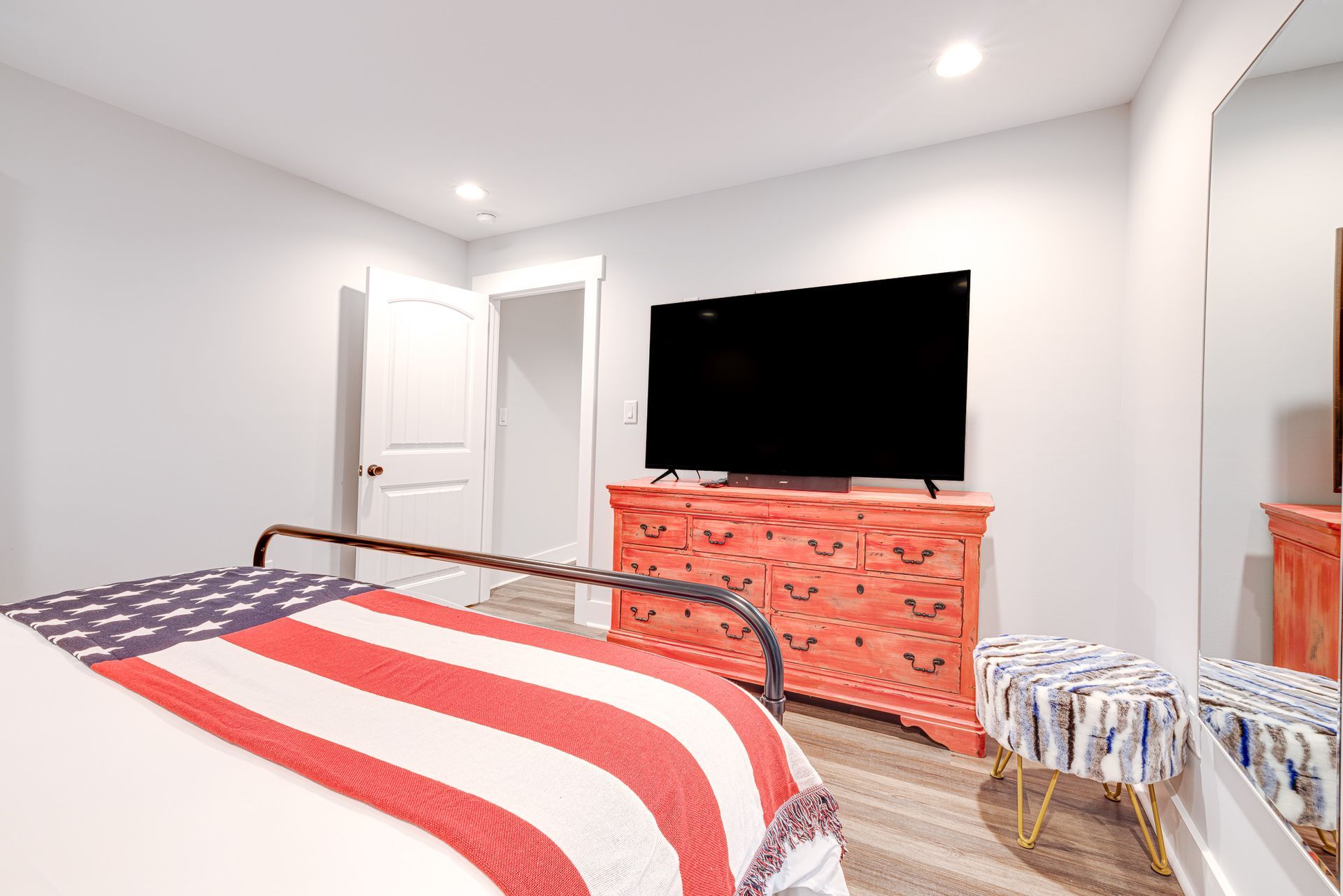 A bedroom with a bed , dresser , television and mirror.