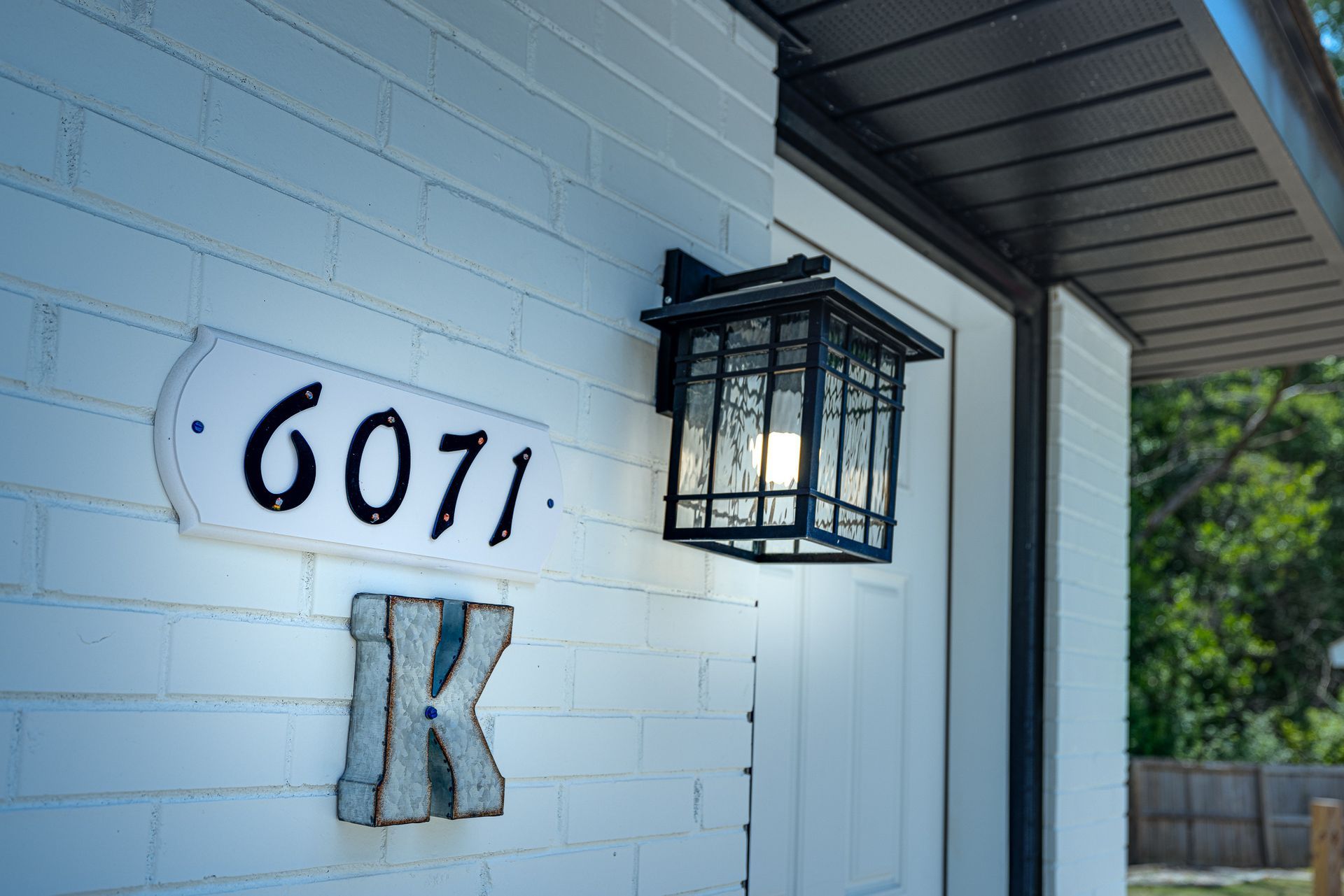 A white brick house with a sign that says ' 6061 k ' on it.