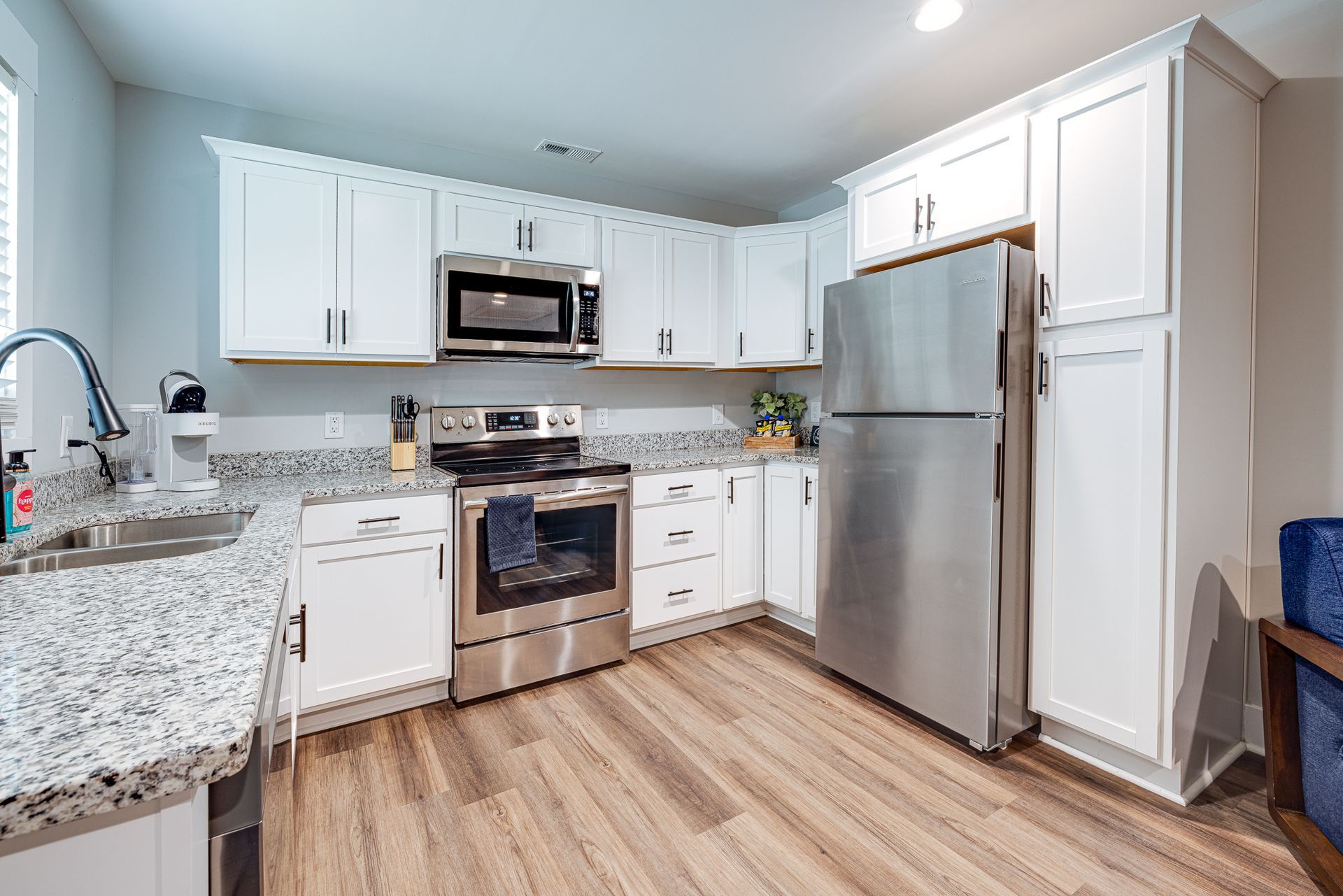 A kitchen with stainless steel appliances , granite counter tops , and white cabinets.