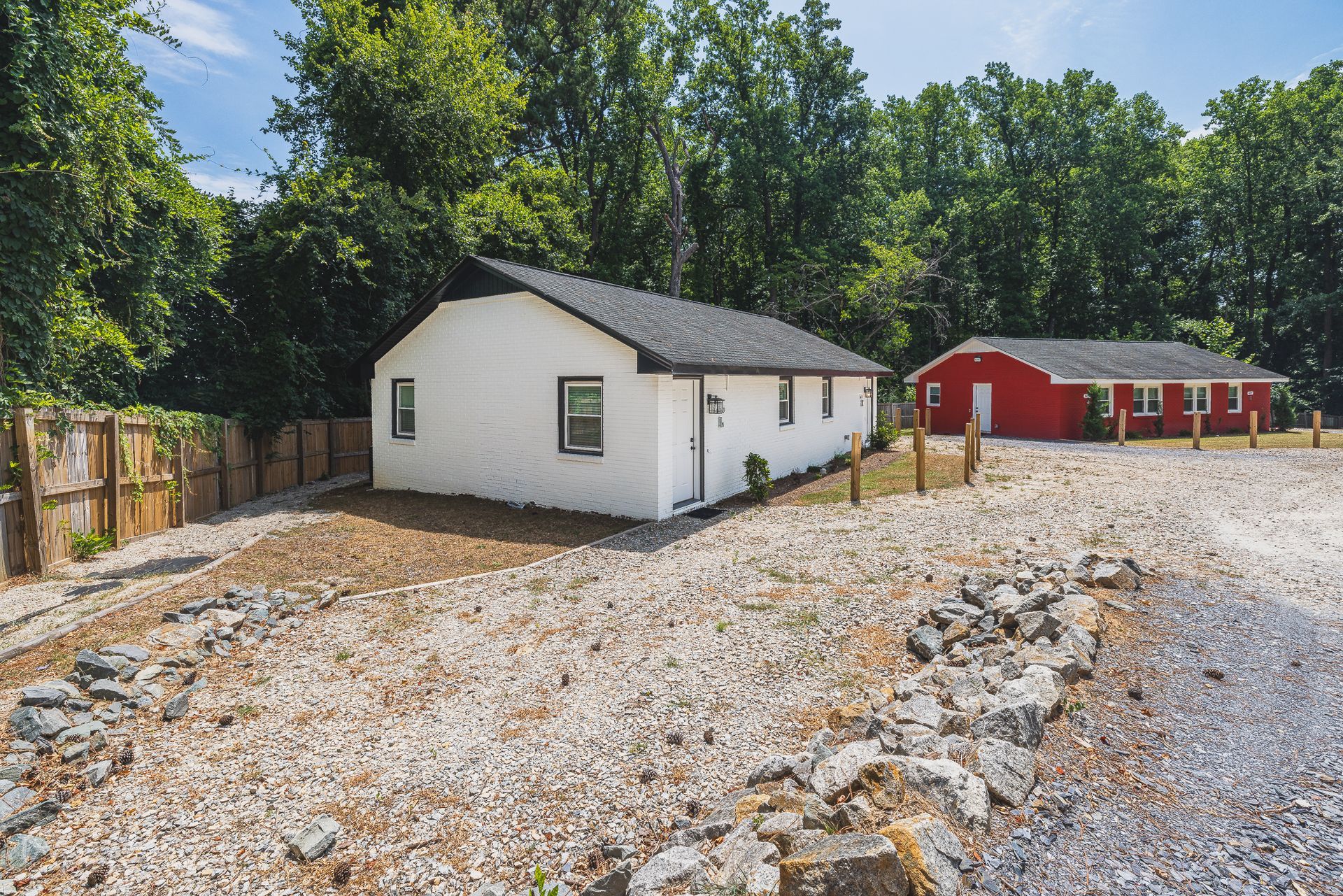 A white house is next to a red house in a gravel lot.