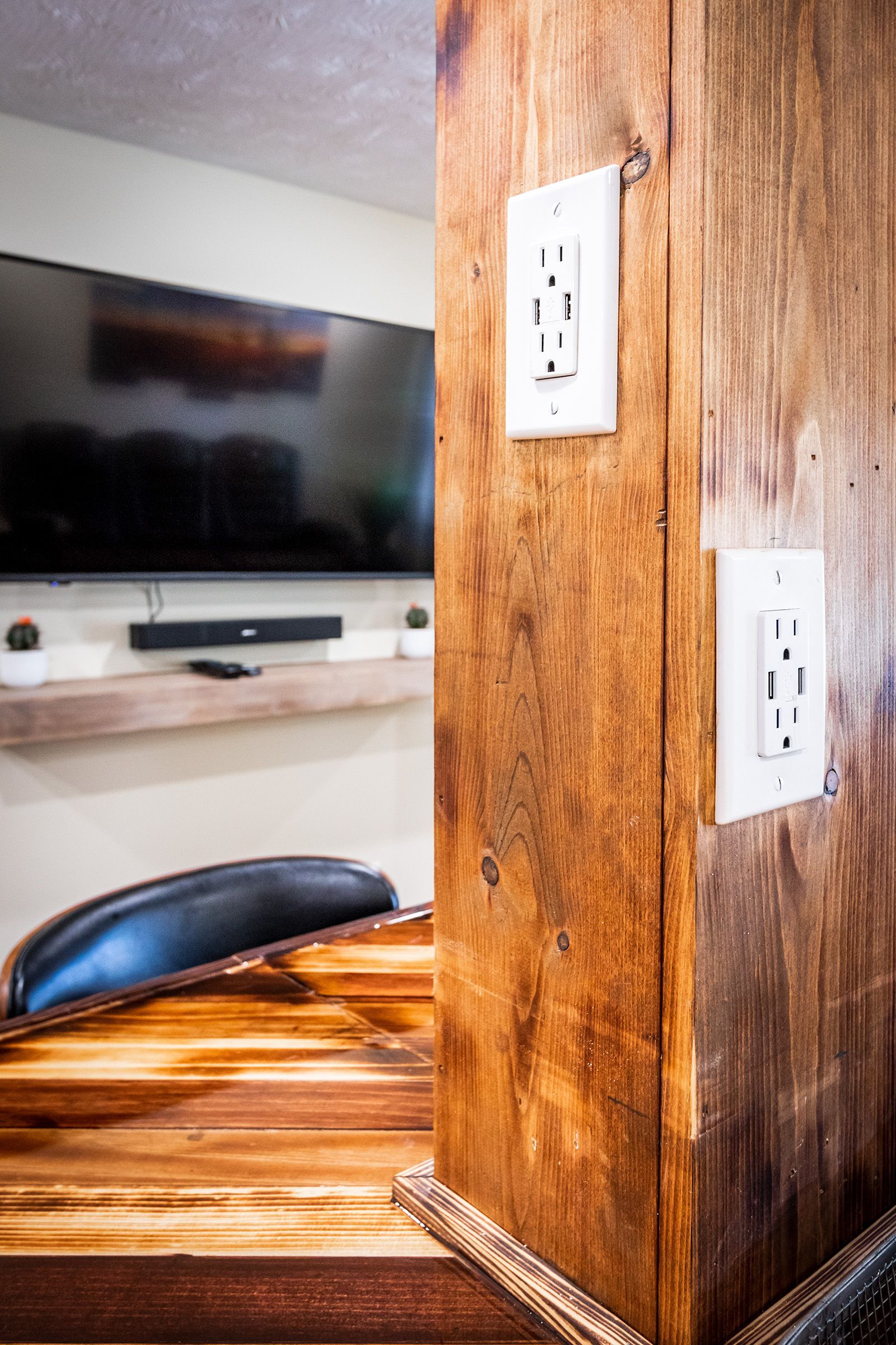 A wooden table with a tv on the wall behind it.