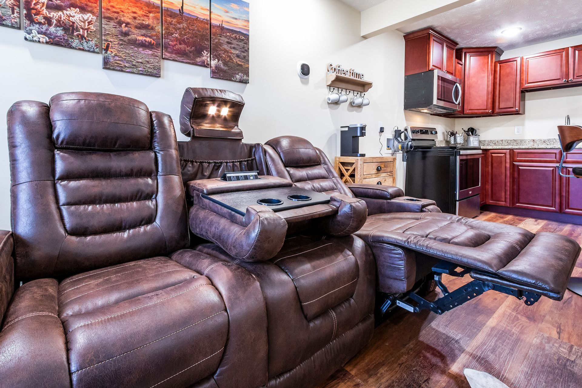 A living room with a couch and chairs and a kitchen.