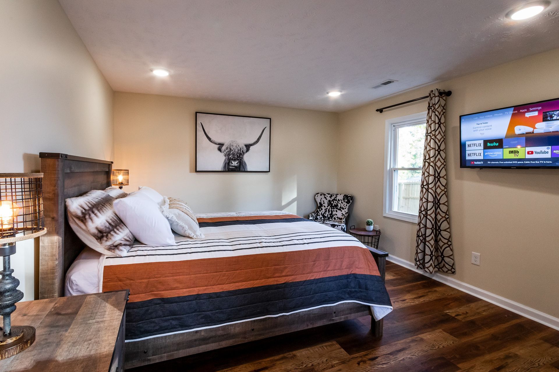 A bedroom with a large bed and a flat screen tv on the wall.