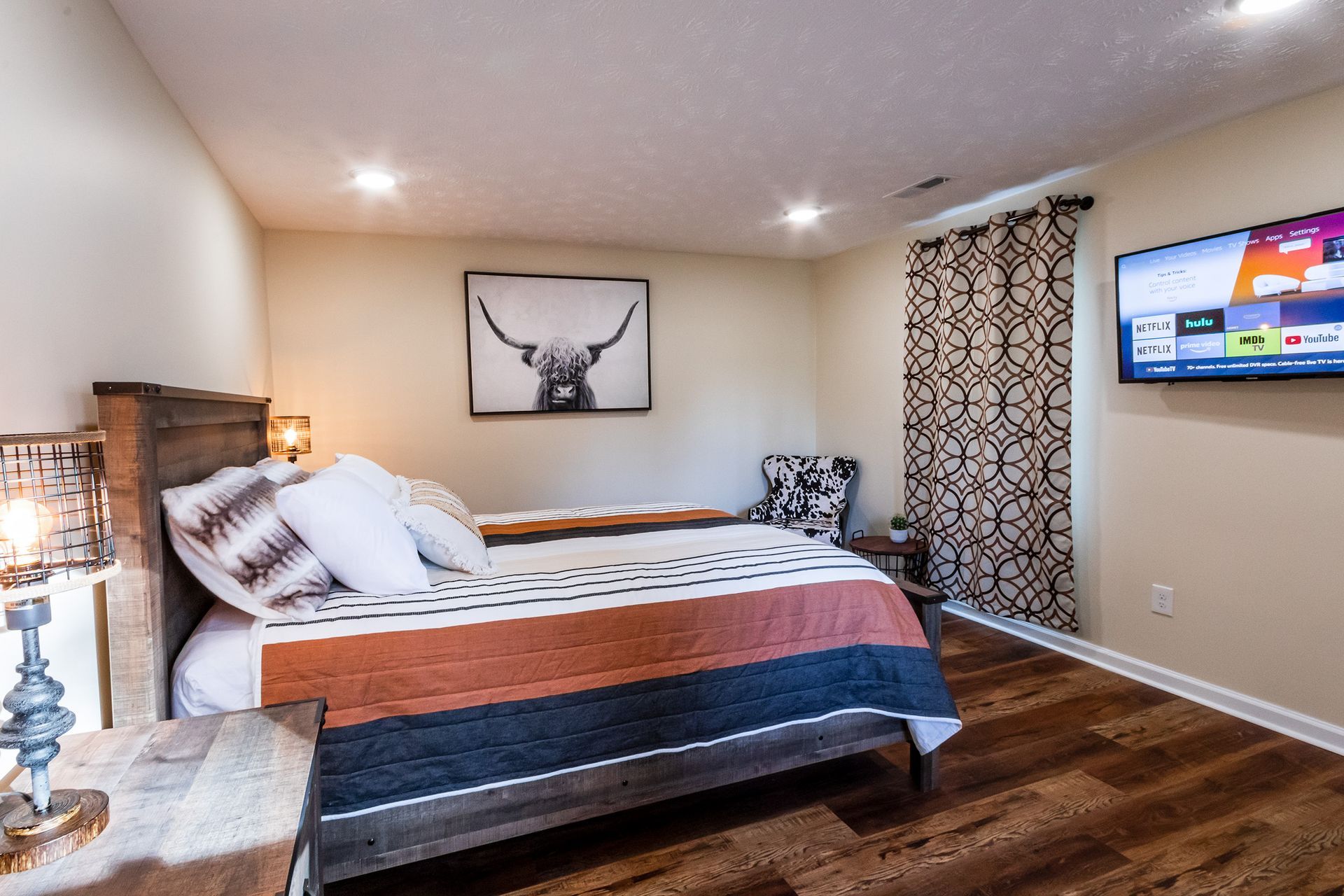 A bedroom with a large bed and a flat screen tv on the wall.