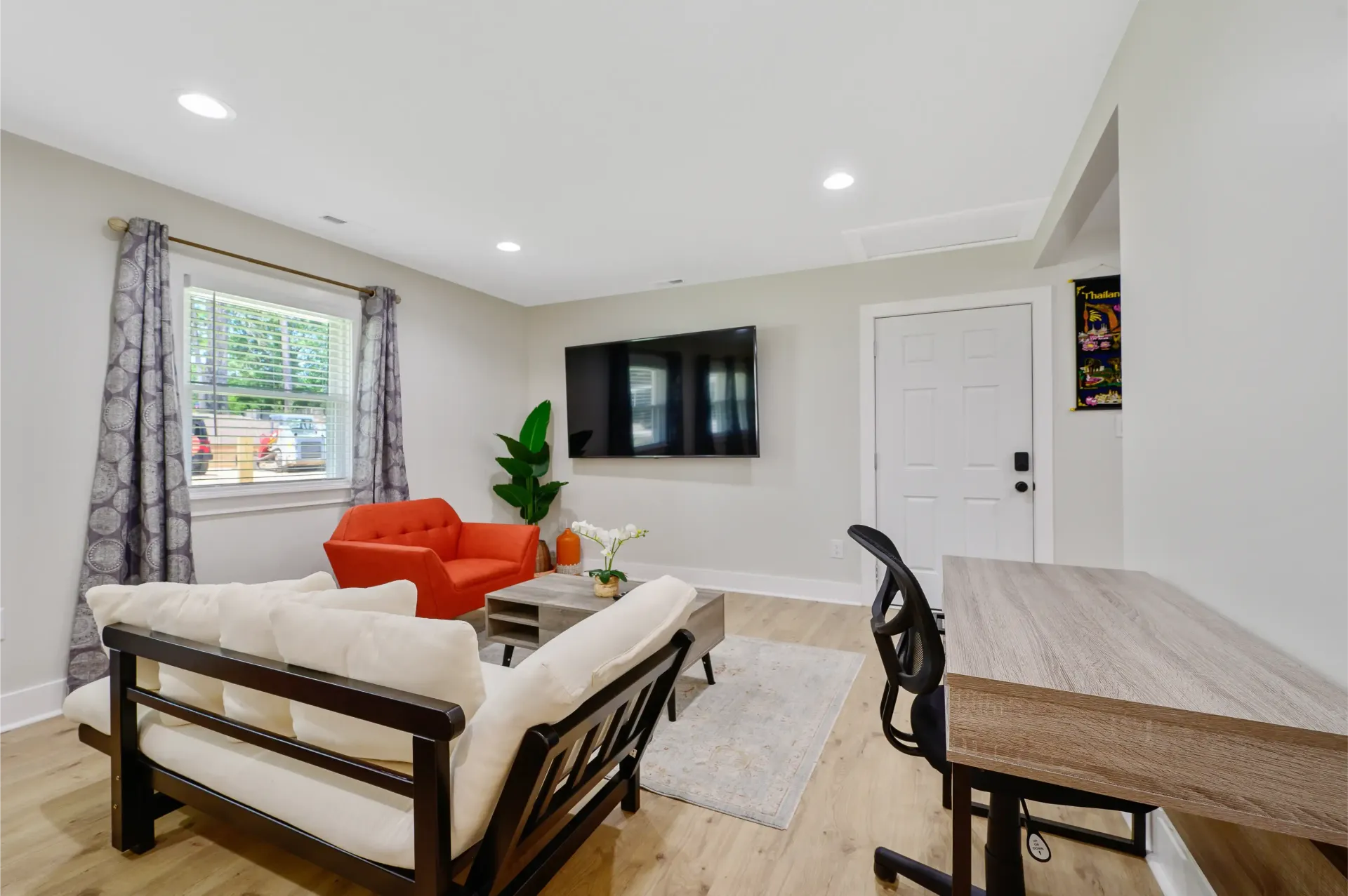 A living room with a couch , chair , desk and television.