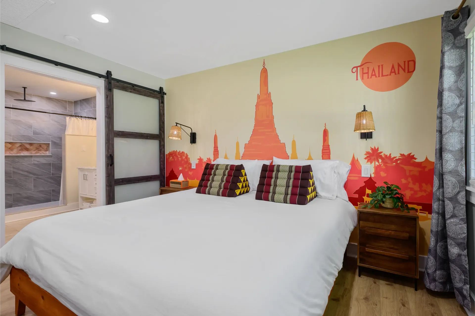 A bedroom with a king size bed and a mural on the wall that says thailand.