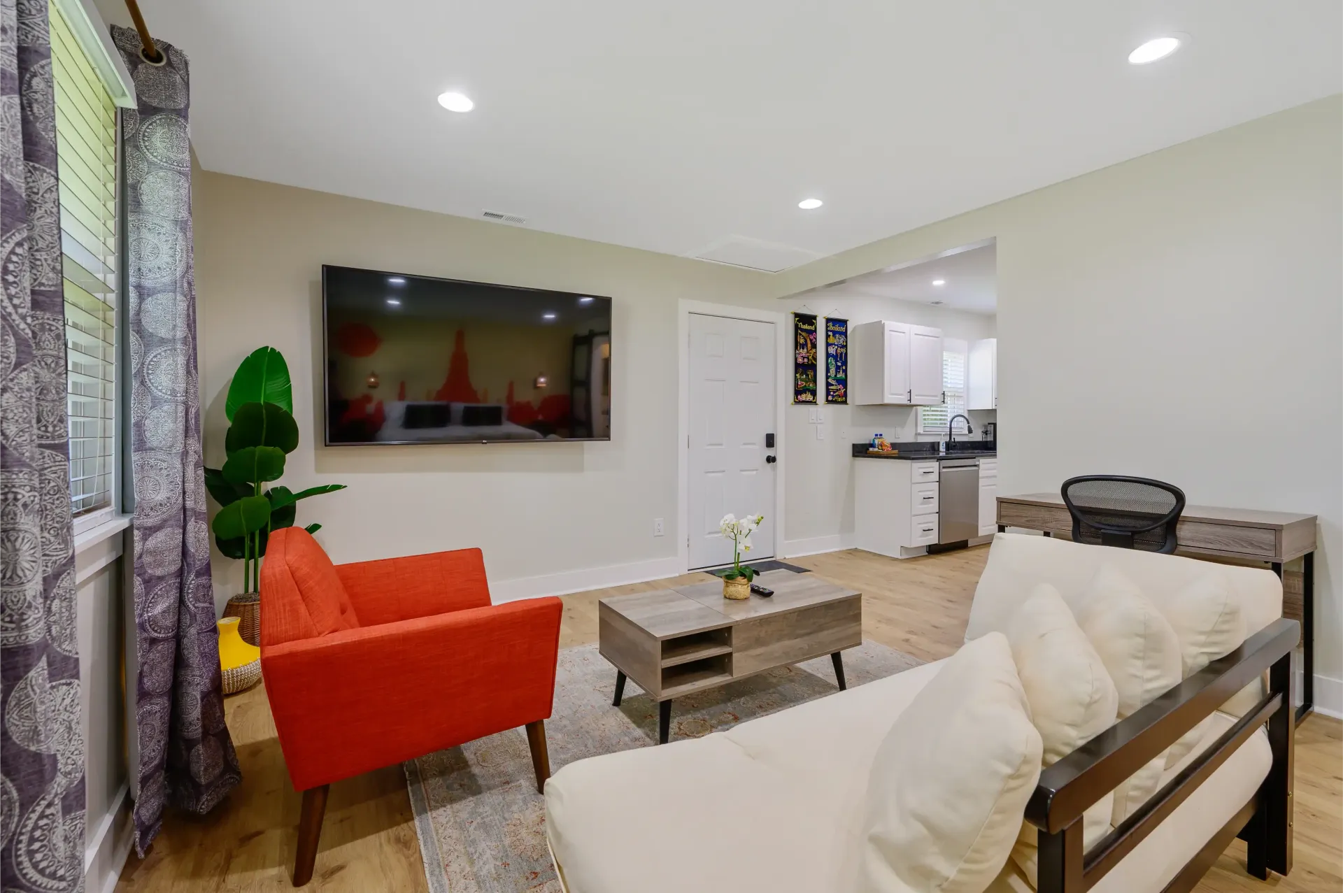 A living room with a couch , chair , coffee table and flat screen tv.