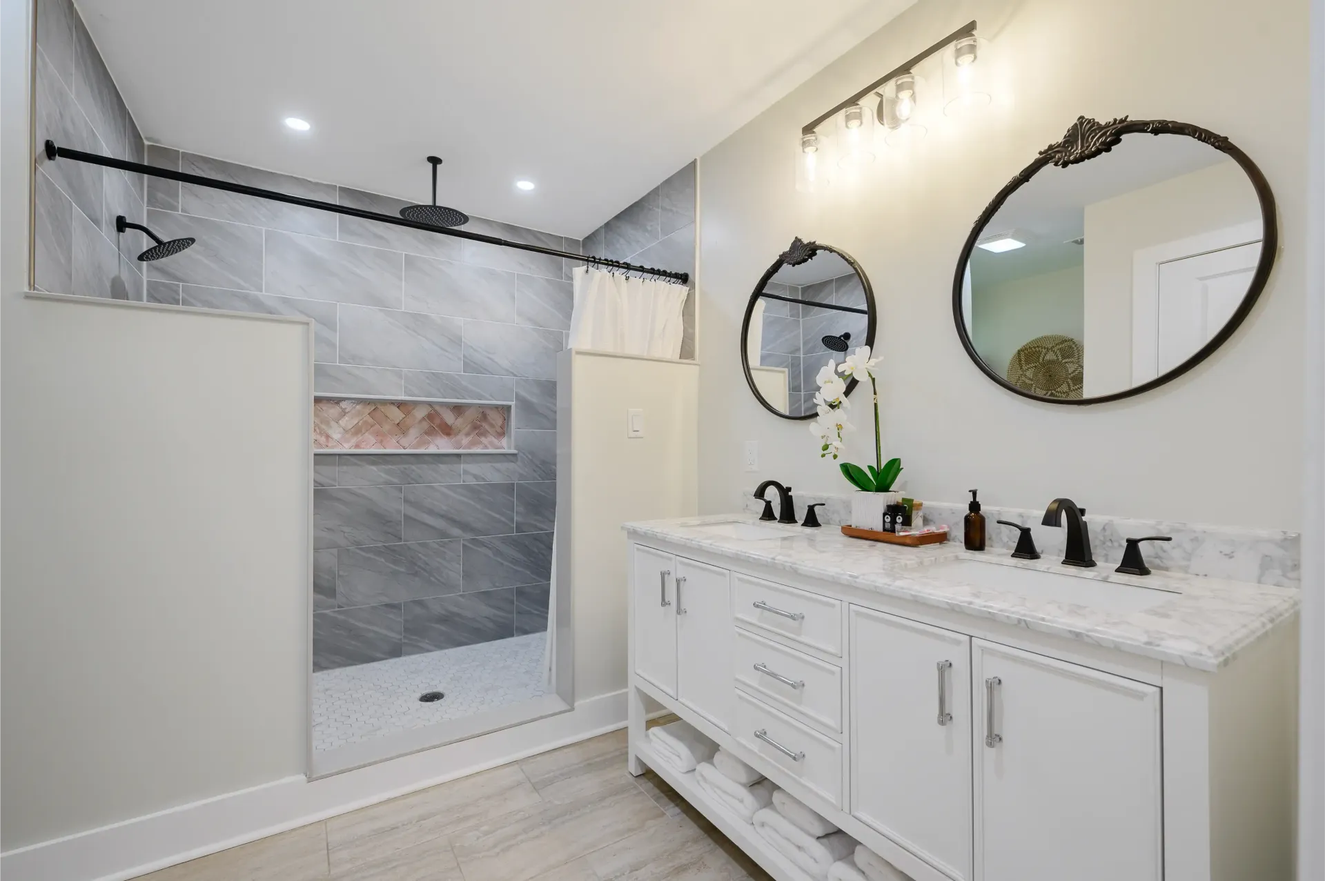 A bathroom with two sinks and a walk in shower.