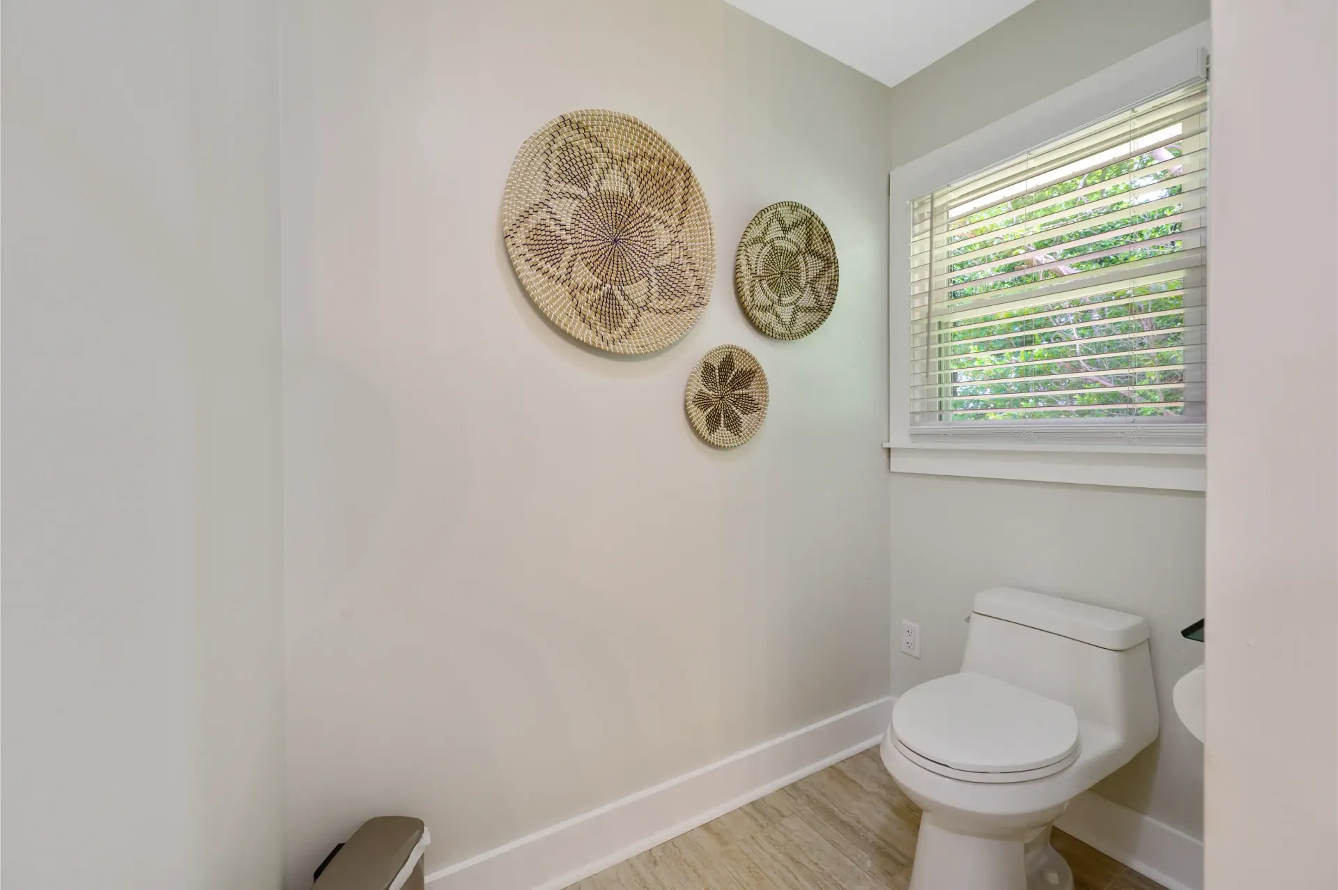 A bathroom with a toilet , sink , and window.