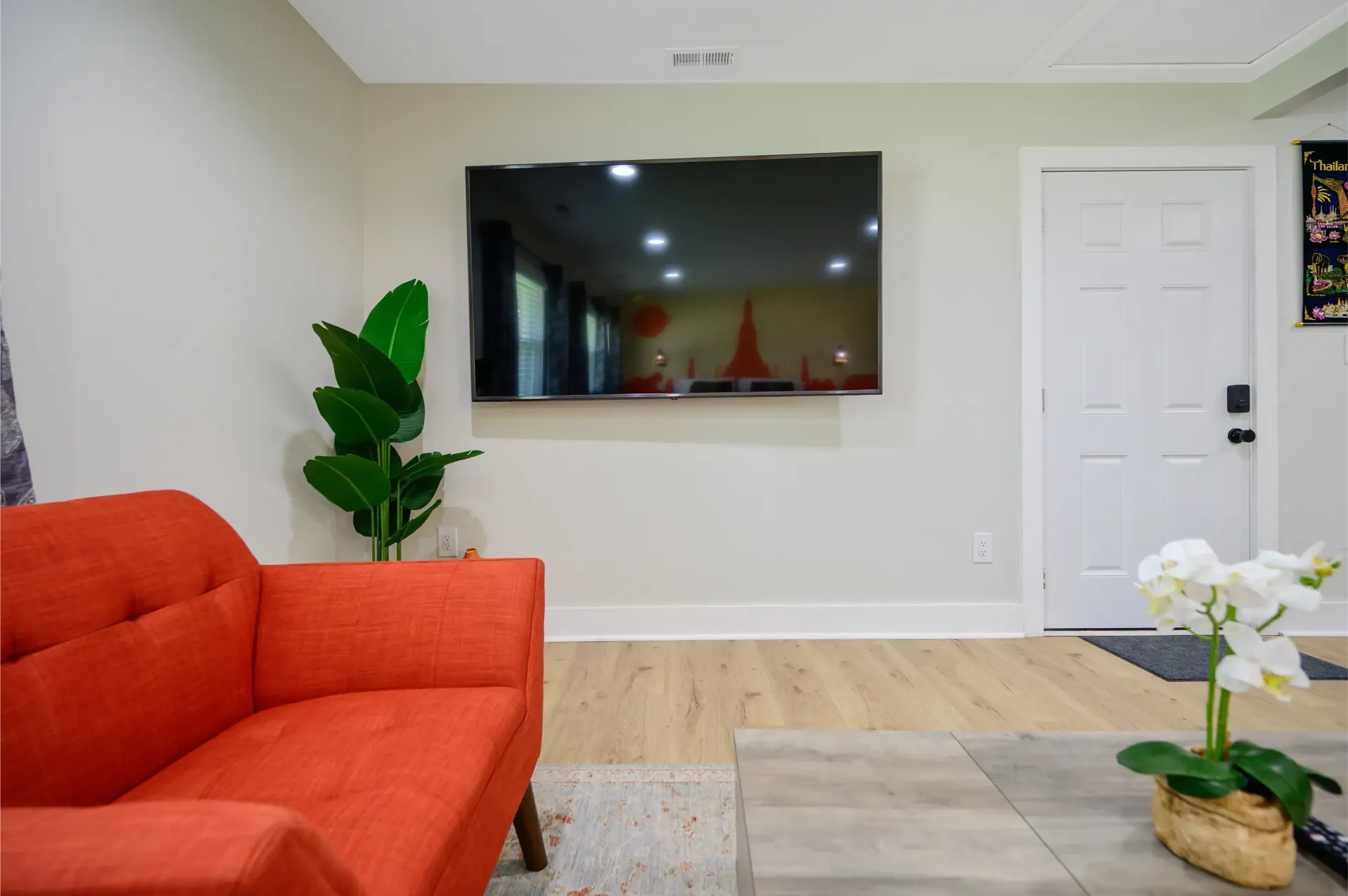 A living room with a red couch and a flat screen tv on the wall.