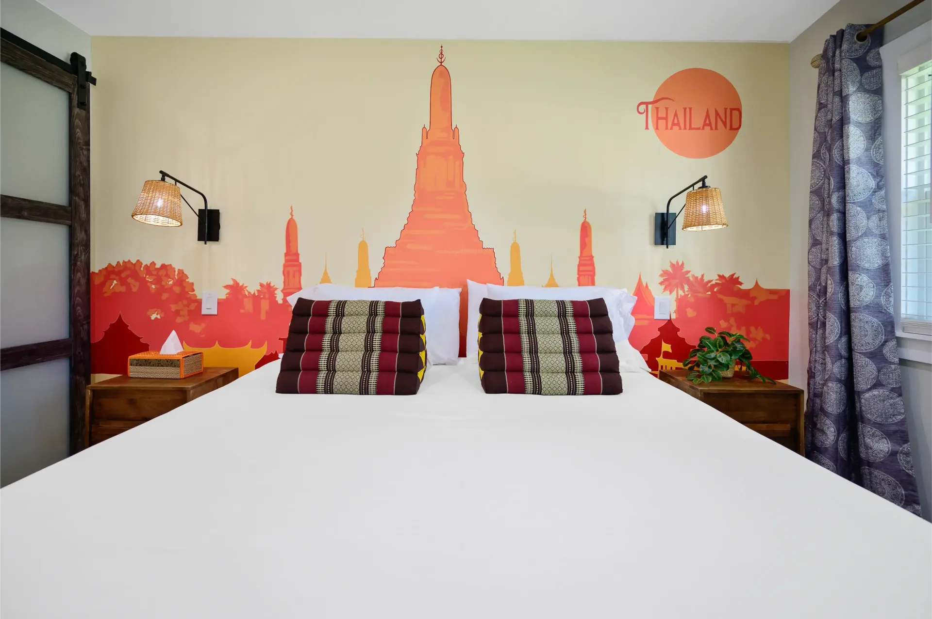A bedroom with a bed and a painting of a temple on the wall.