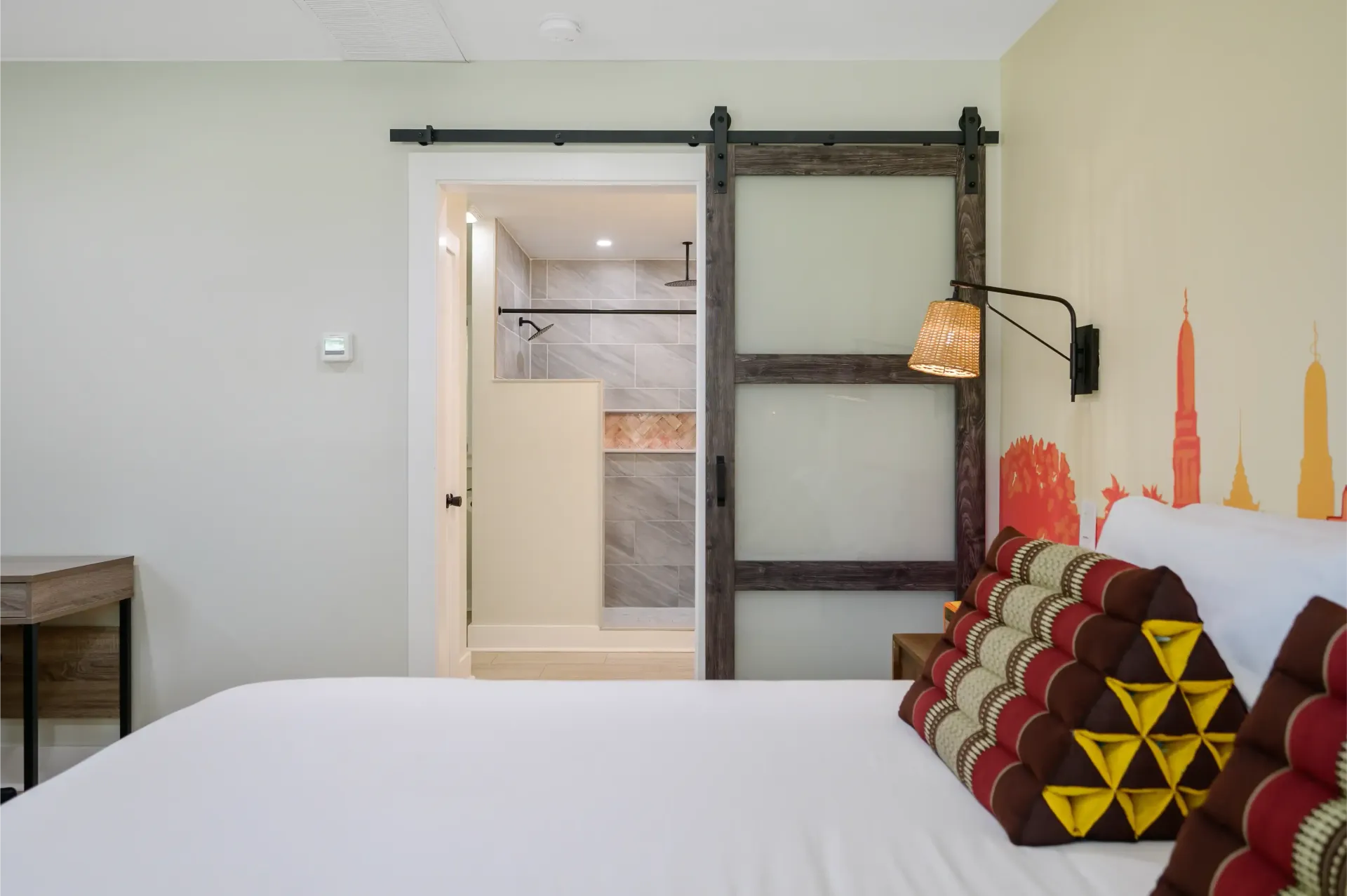 A bedroom with a sliding barn door leading to a bathroom.