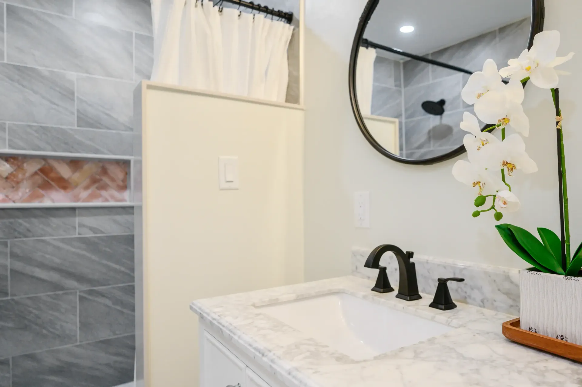 A bathroom with a sink , mirror and shower.