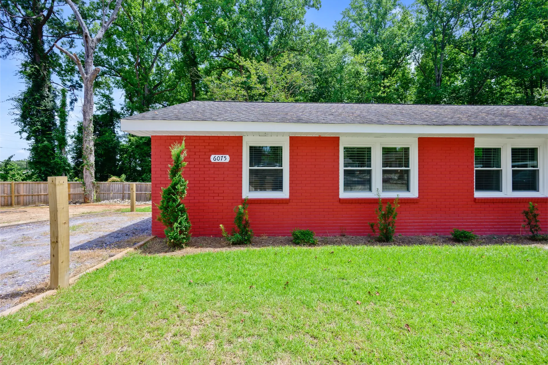 A red house with white windows is sitting on top of a lush green lawn.