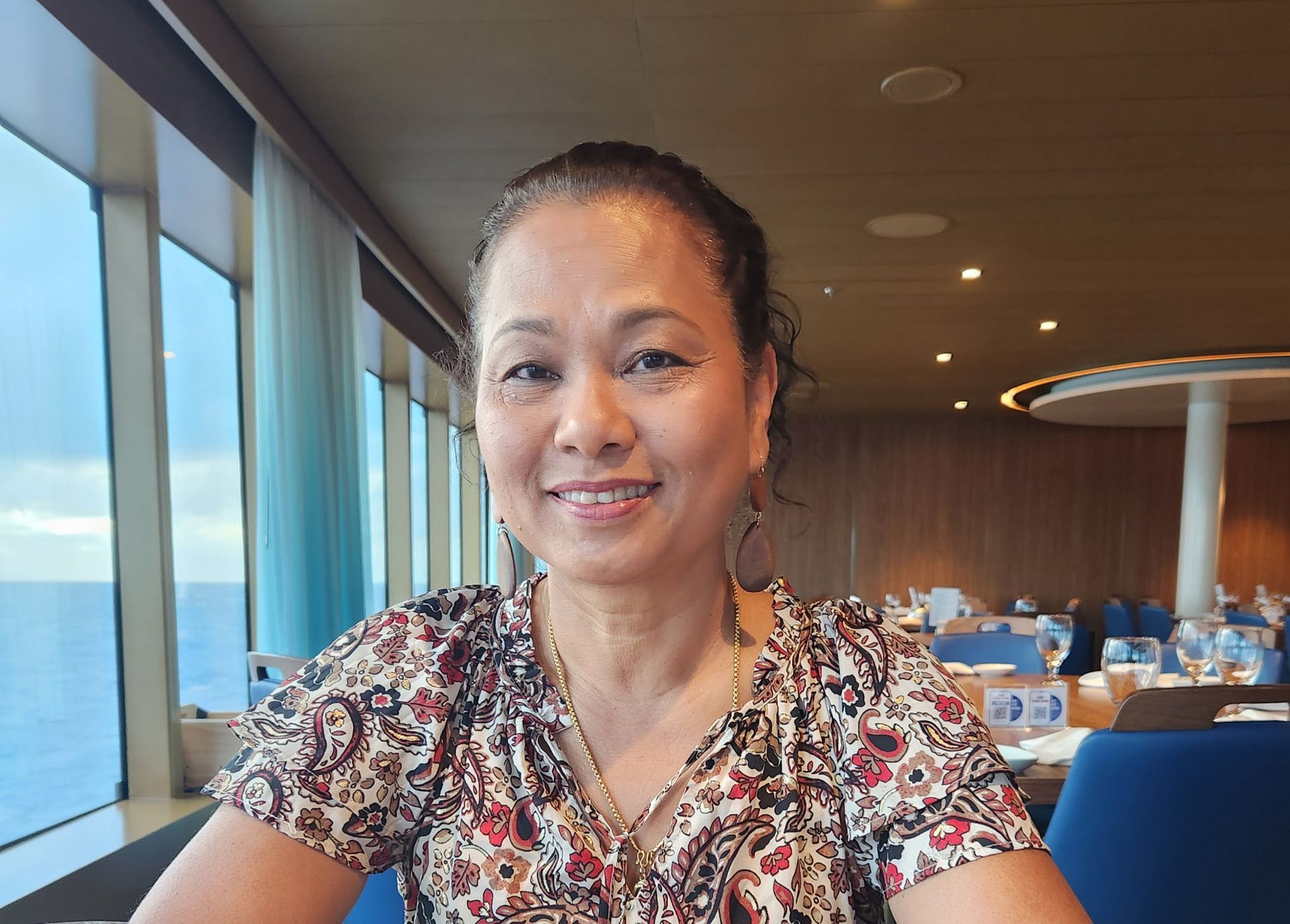 A woman is sitting in front of a window on a cruise ship.