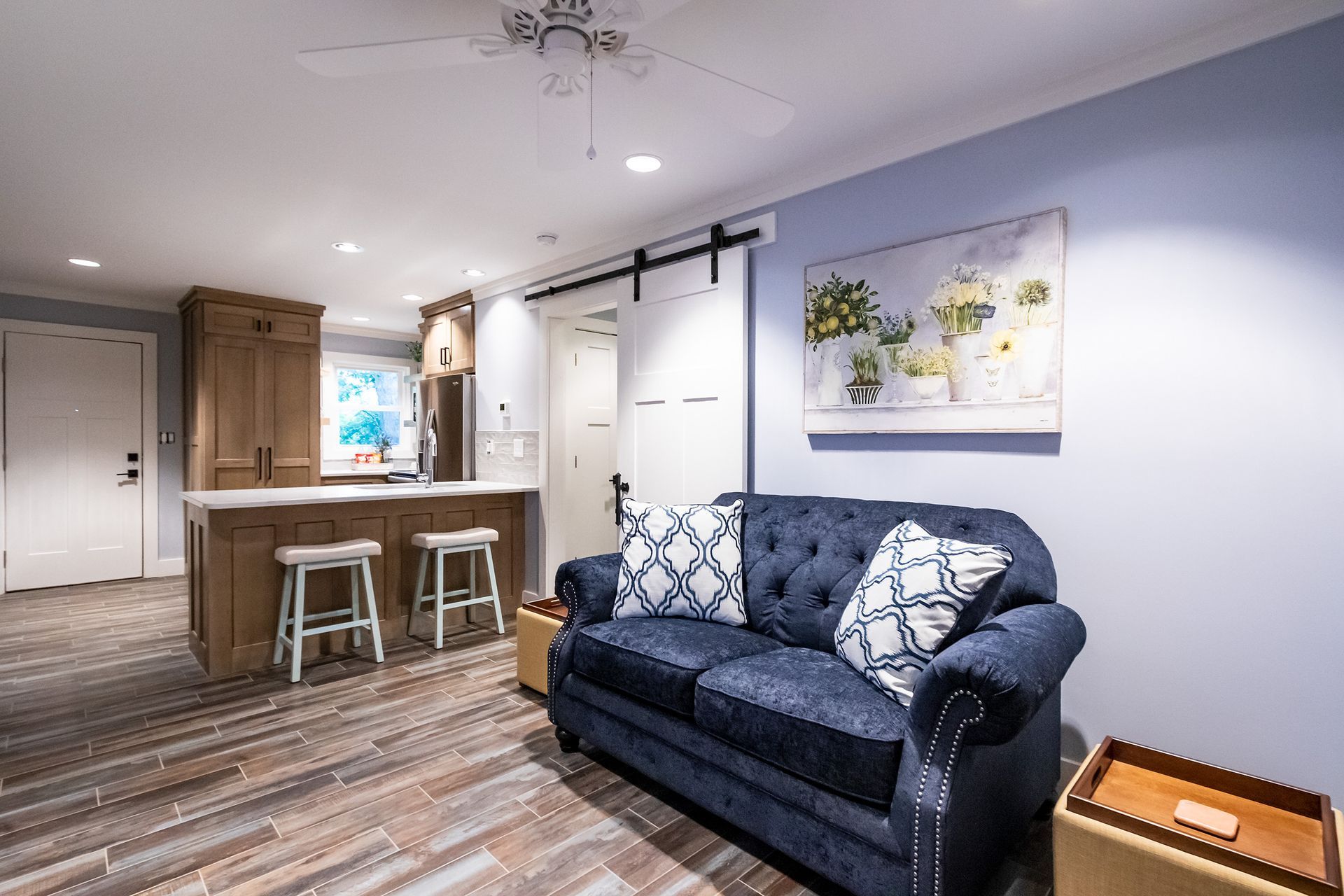 A living room with a blue couch and a painting on the wall.