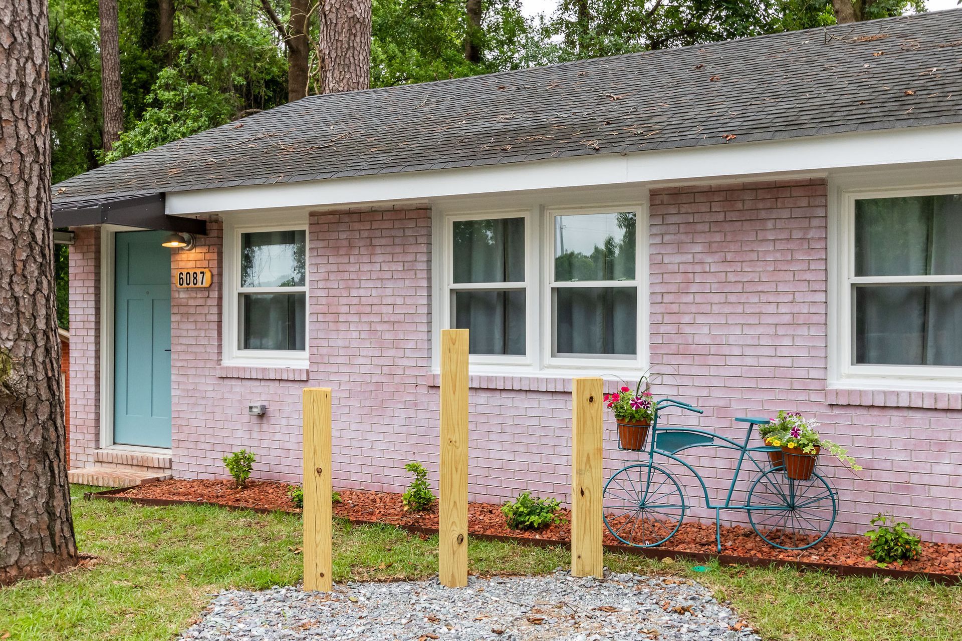 A pink brick house with a blue door and a bicycle in front of it.