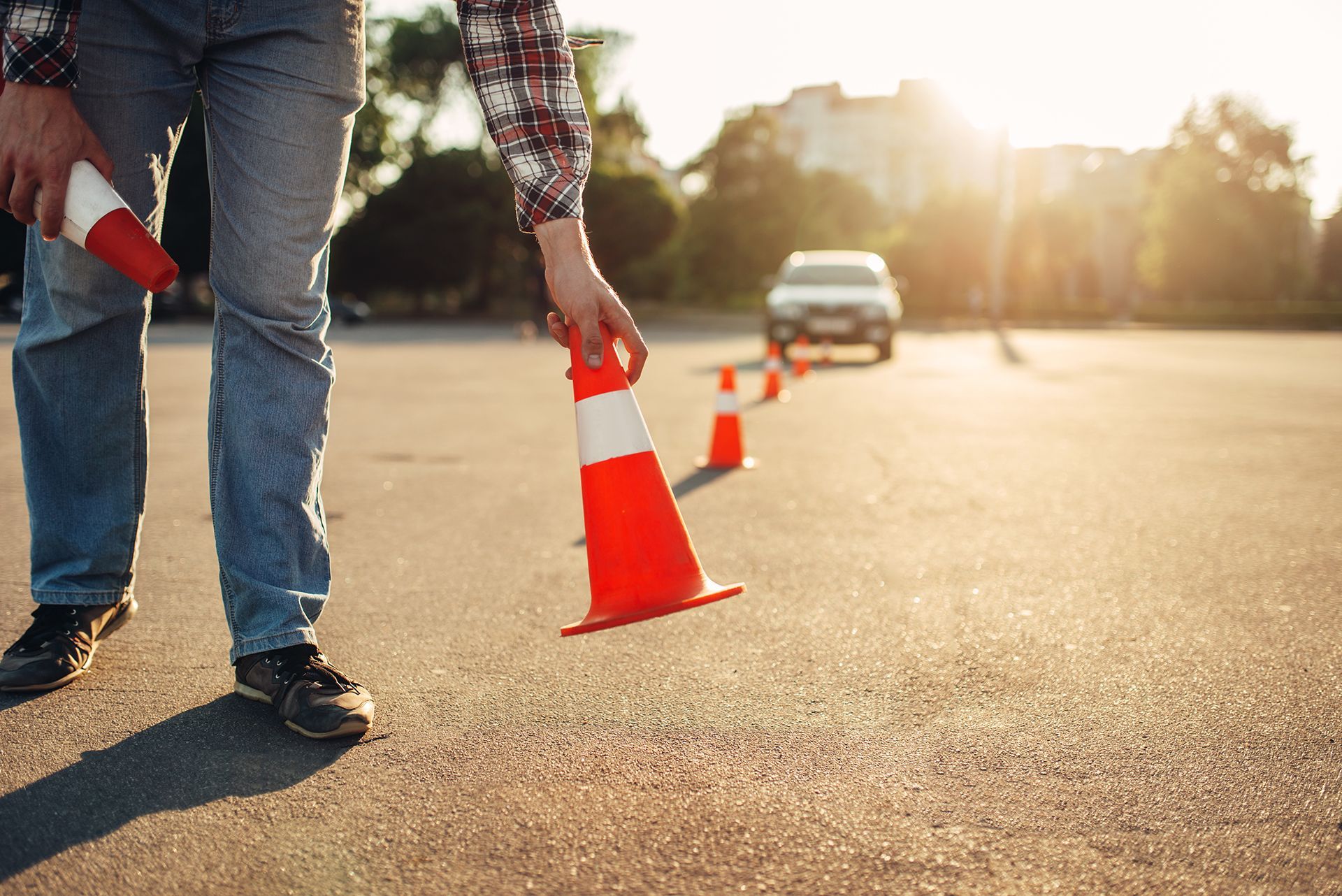 A man is holding a traffic cone on the side of the road.