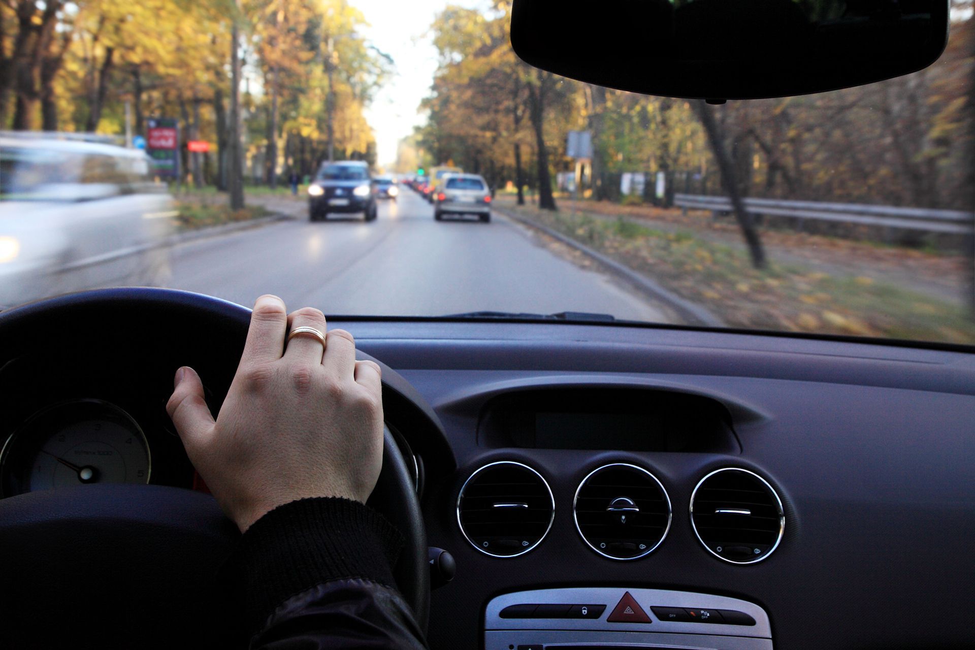 A person is driving a car with a ring on their finger.