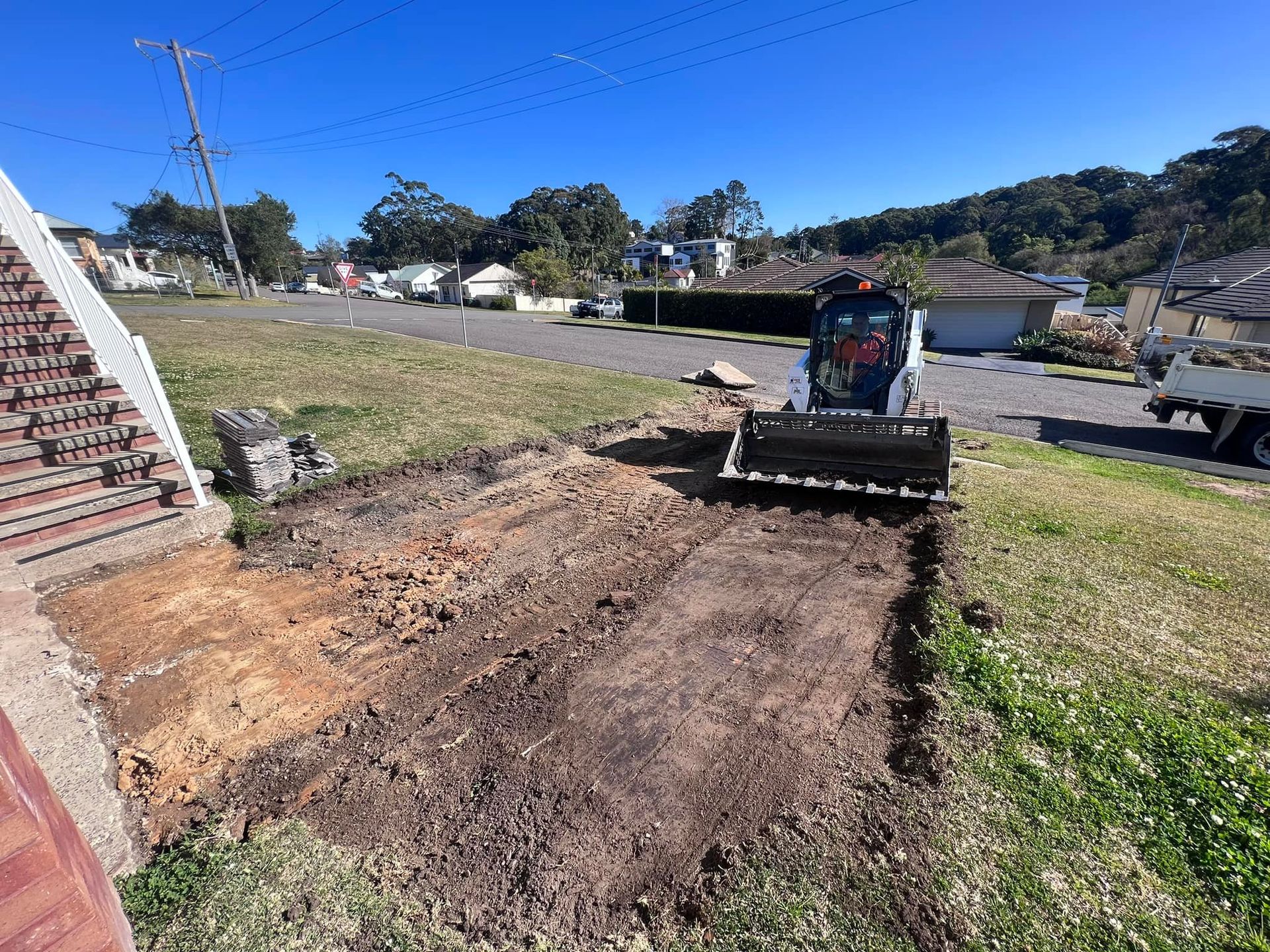 A bulldozer is digging a hole in a yard.