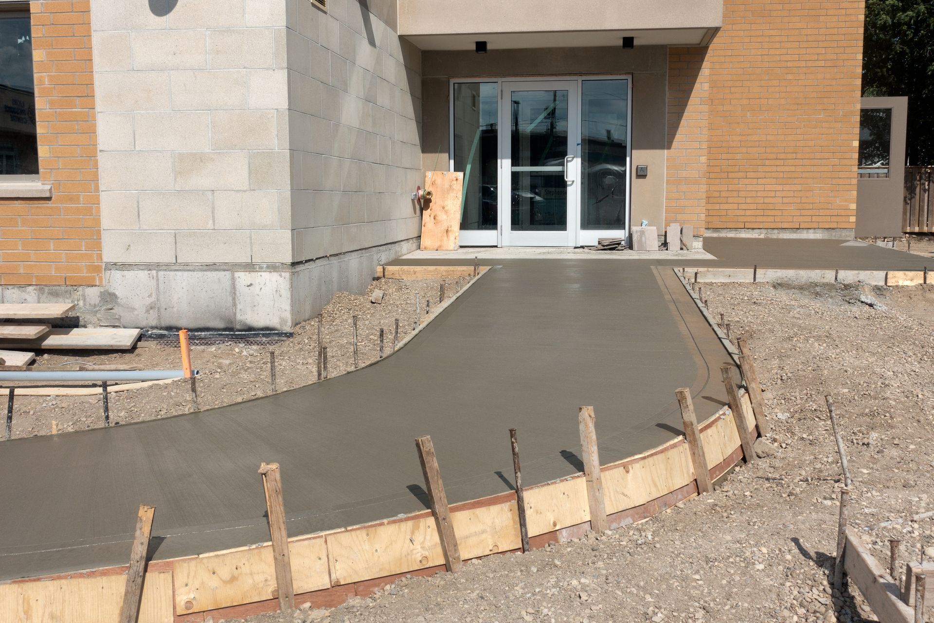 A freshly poured cement sidewalk leading into a new building.
