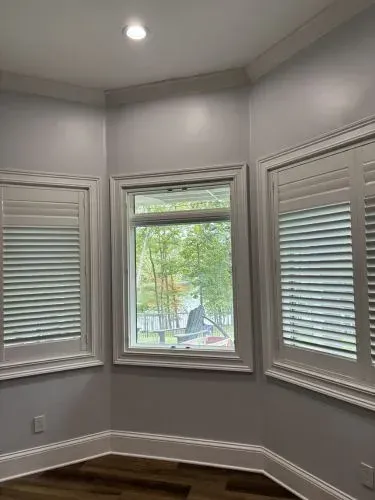 White bathroom with a built-in shower niche, vanity, and mirror under wall sconces.