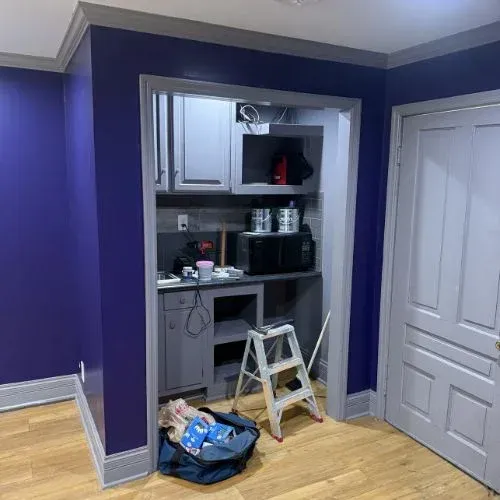 Small kitchen pass-through with purple walls, a step ladder, and renovation tools on the floor