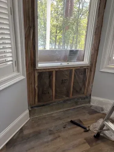 Small kitchen nook under renovation with cabinets, countertop, step stool, and tools against a purple wall