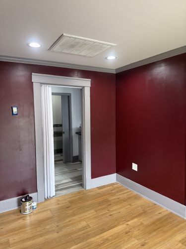 Empty room with burgundy walls, wood floor, and an open doorway with white curtains