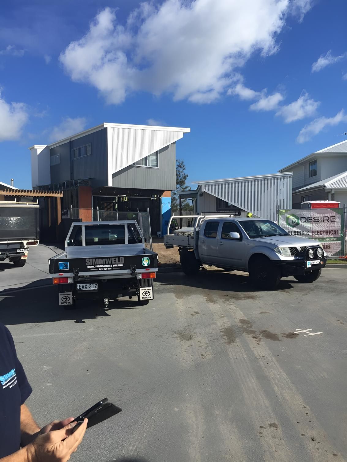 A Man is Standing in Front of a Building With Trucks Parked in Front of It — Simmweld Metal Fabrication and Welding In South Murwillumbah, NSW