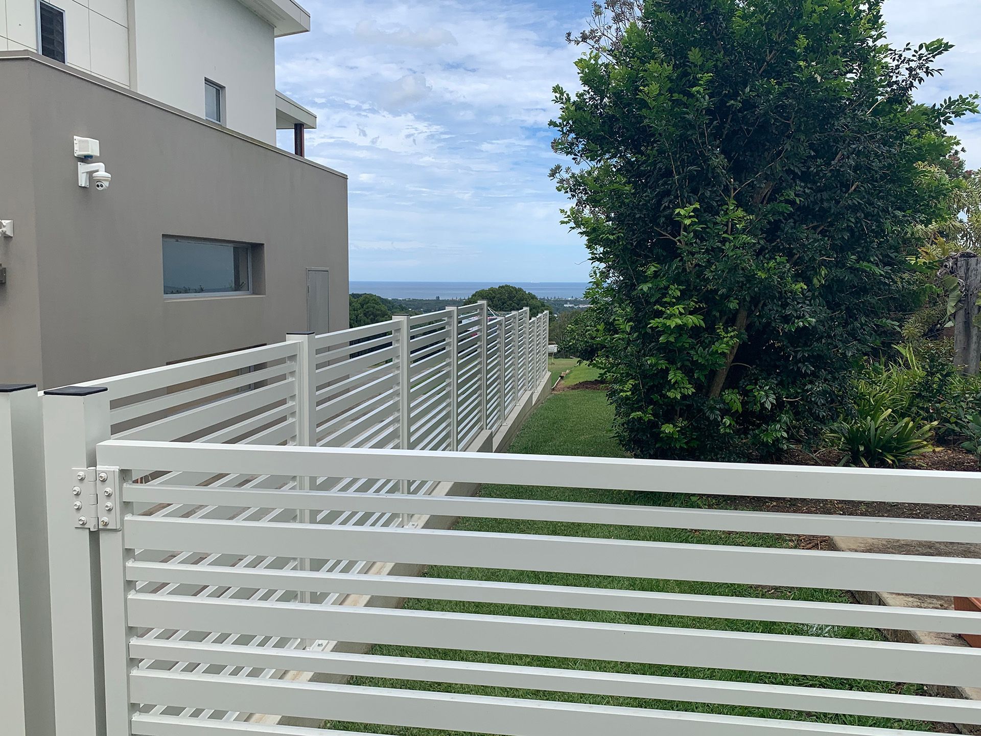 A white fence surrounds a yard with a view of the ocean. — Simmweld Metal Fabrication and Welding In Banora Point, NSW