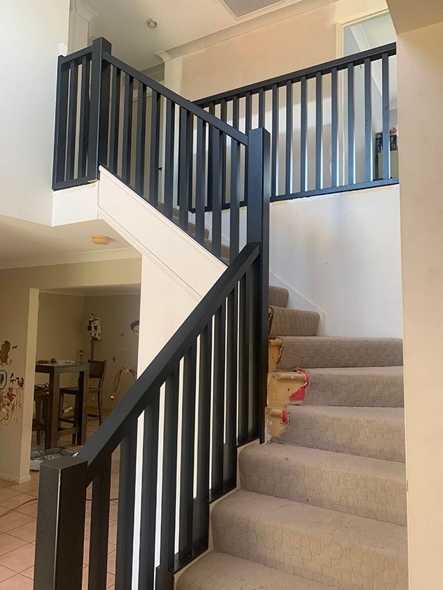 A Staircase With a Black Railing in a House — Simmweld Metal Fabrication and Welding in Murwillumbah, NSW