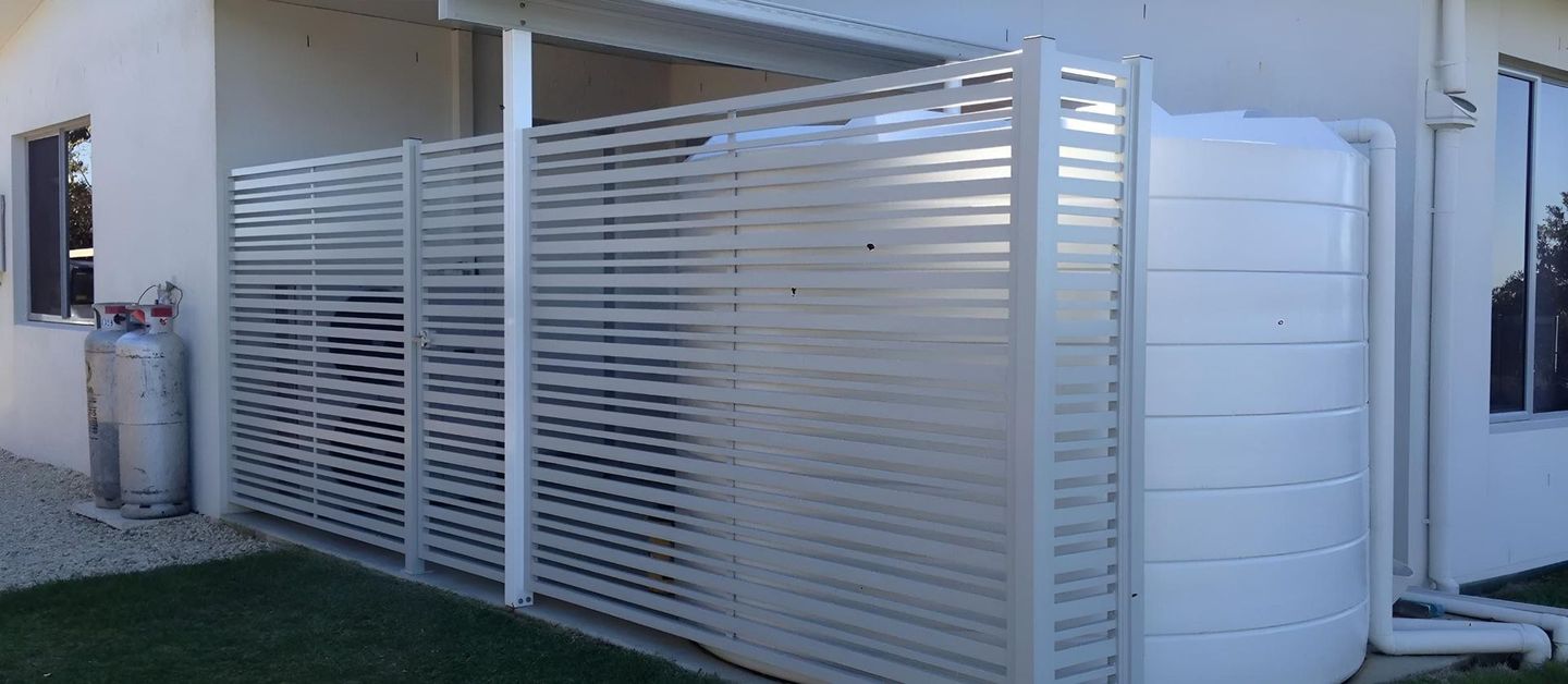 A White Water Tank is Sitting Next to a White Fence — Simmweld Metal Fabrication and Welding In South Murwillumbah, NSW